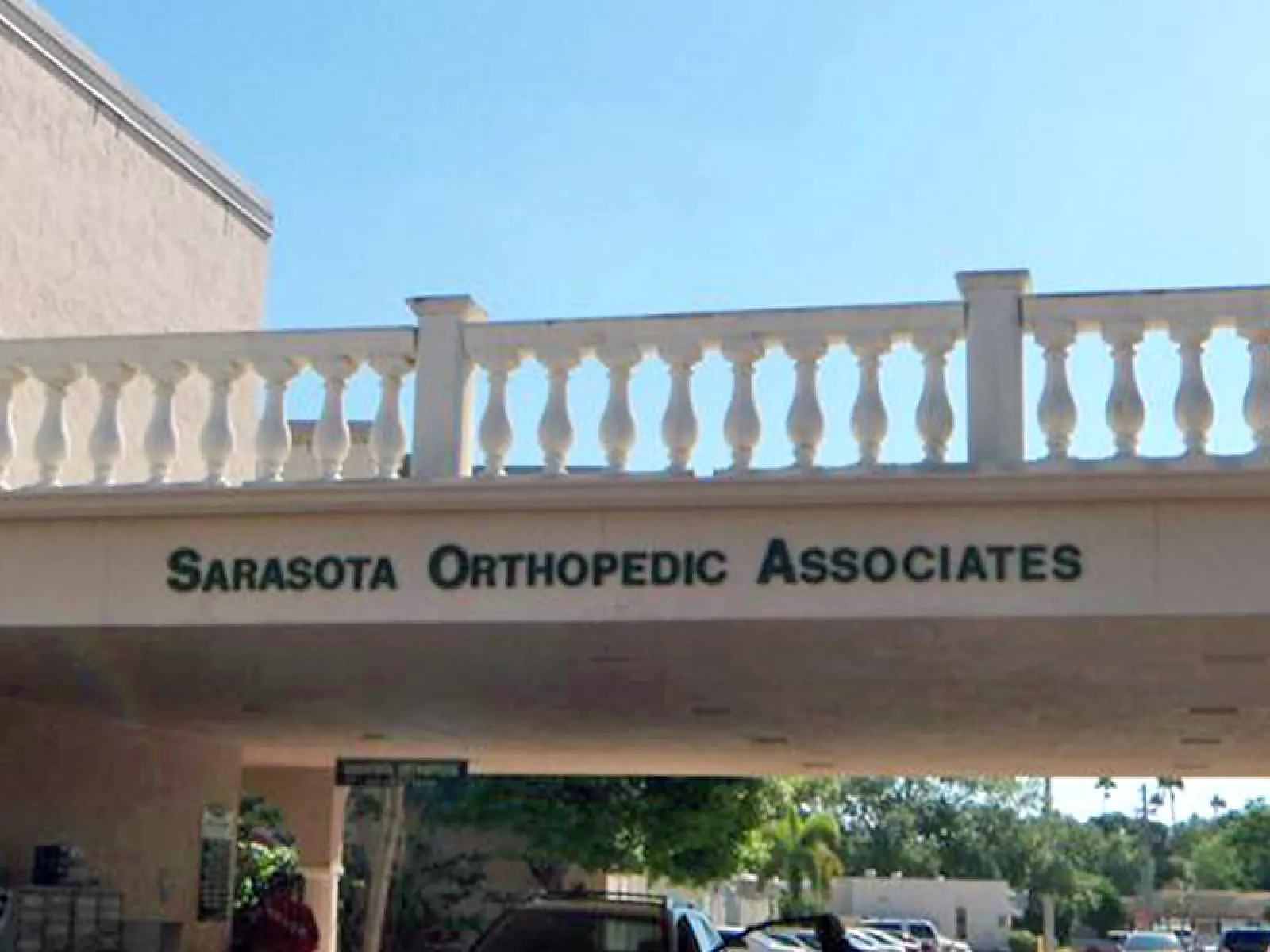 Exterior entrance of Sarasota Orthopedic Associates medical office under a balcony with balustrade.
