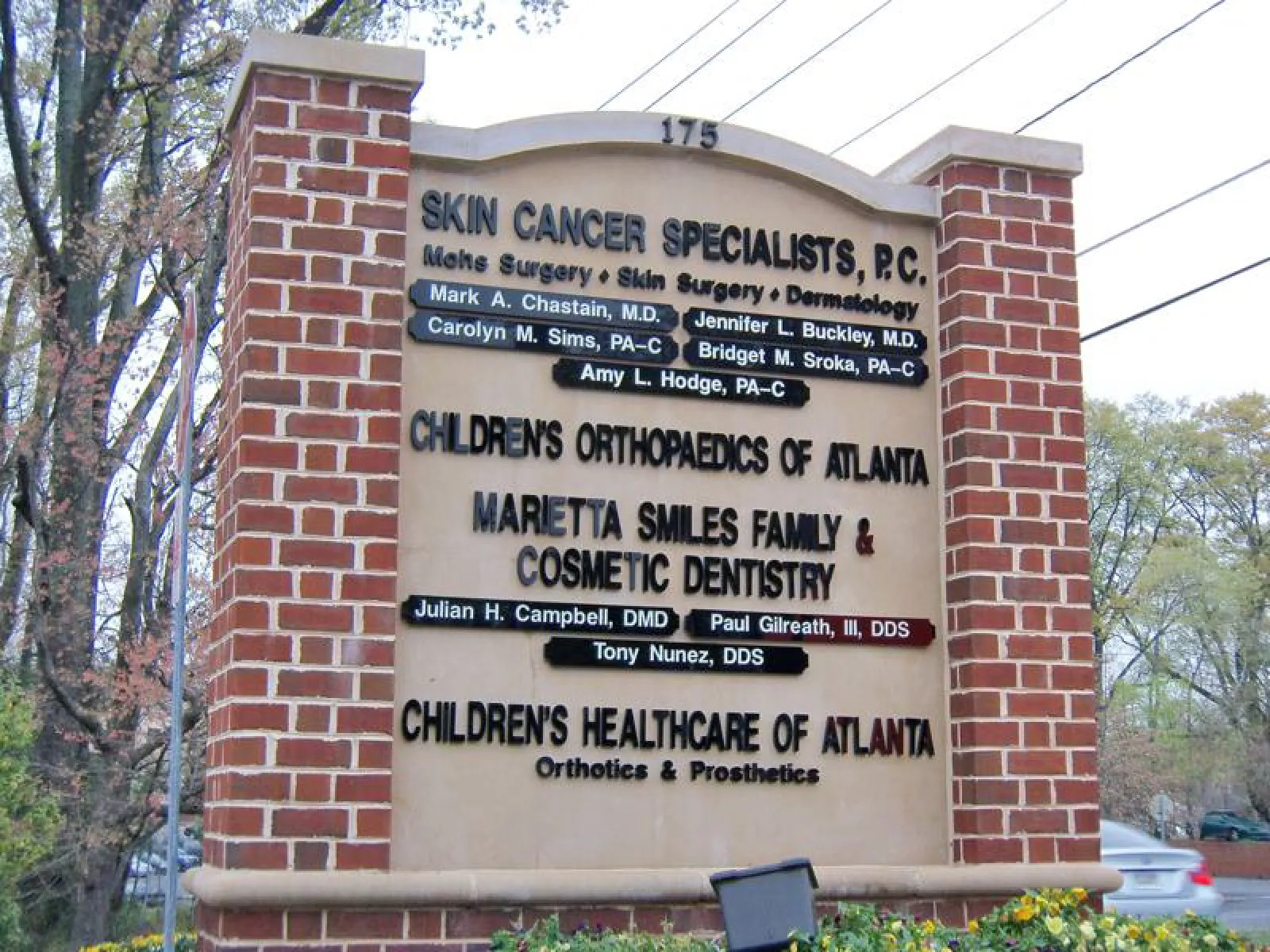 Outdoor medical office sign listing skin cancer specialists, children’s orthopaedics, family dental, and healthcare services.