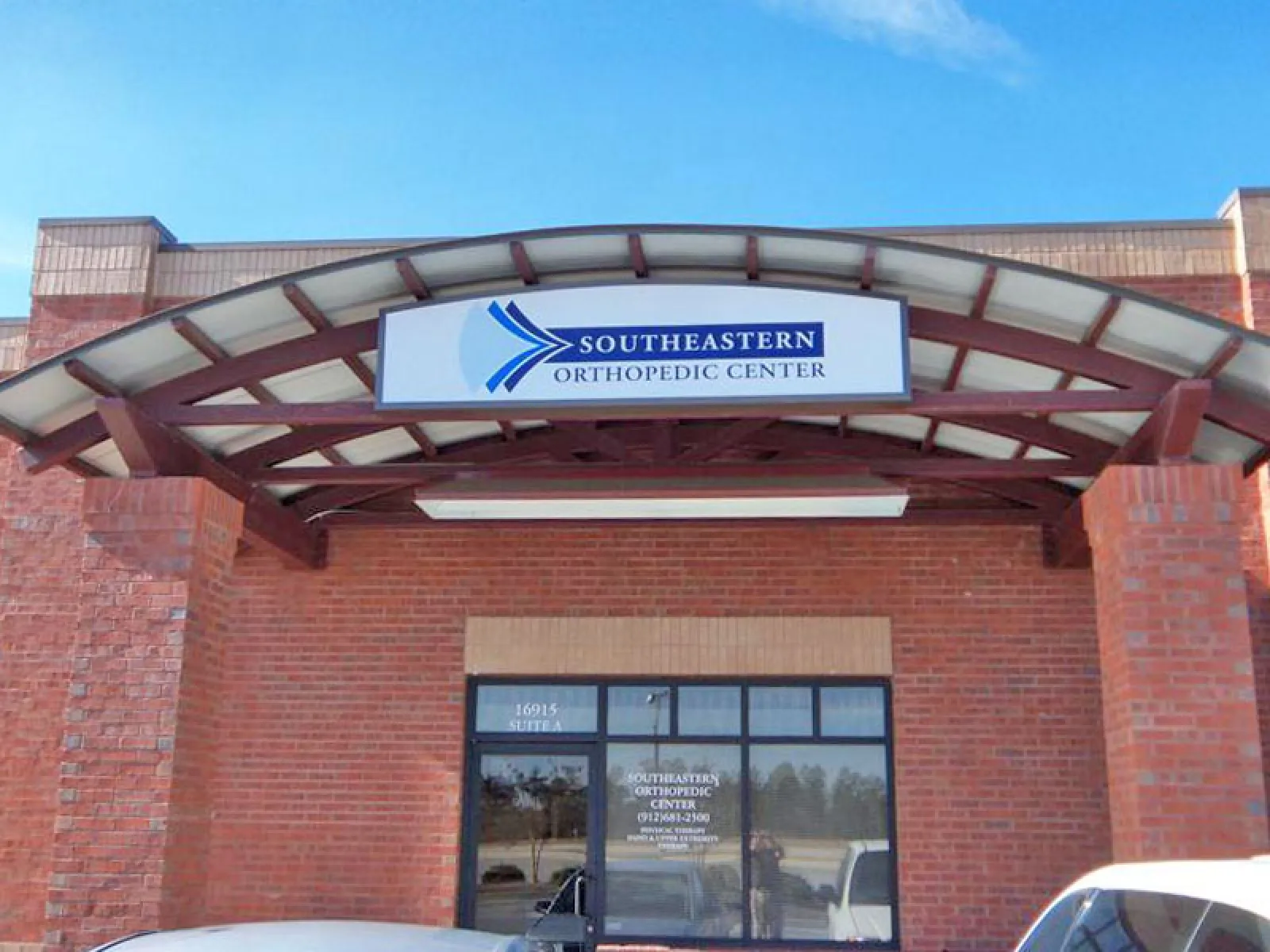 Entrance of Southeastern Orthopedic Center with brick walls and curved metal awning above the glass door.