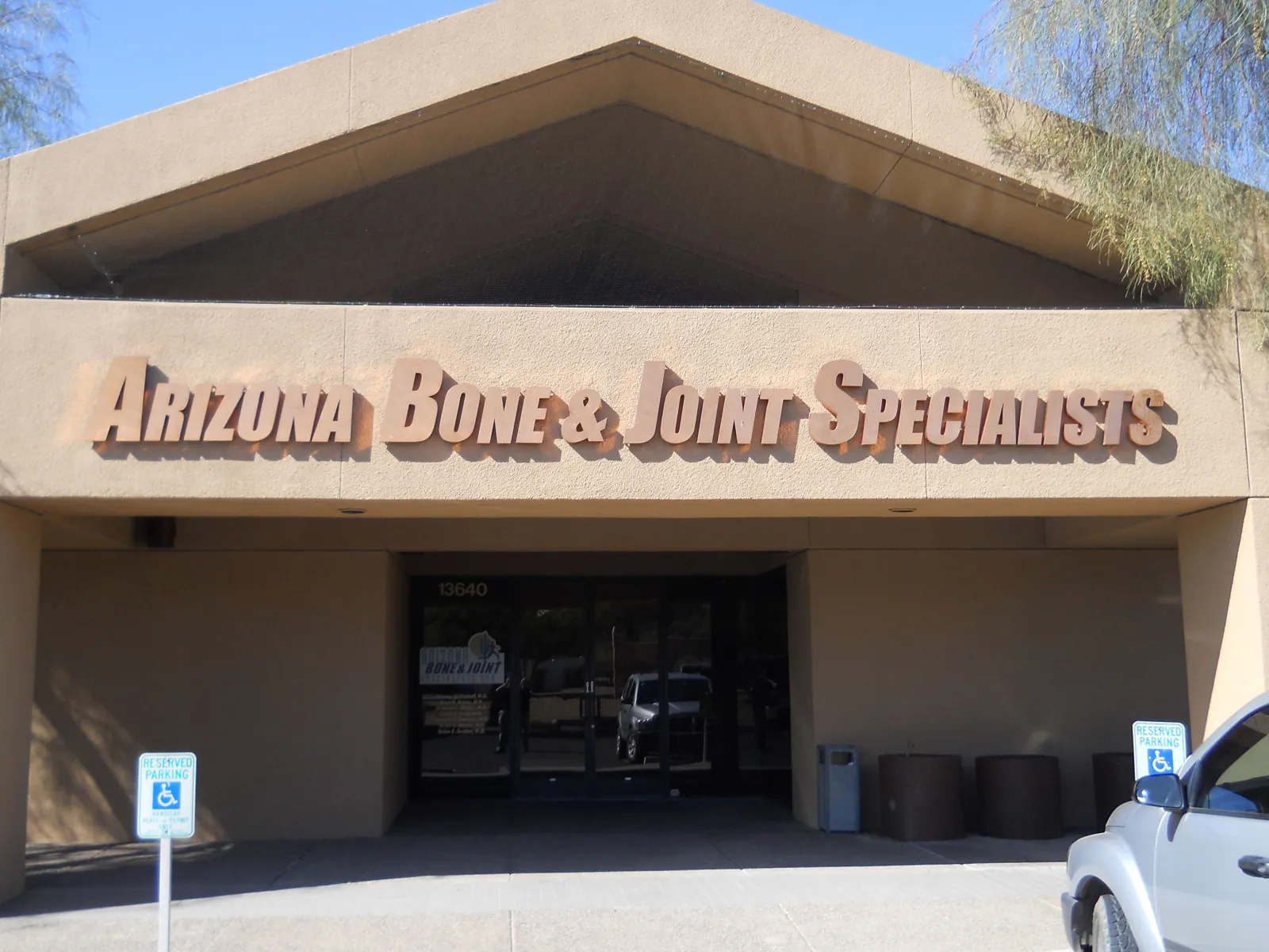 Building entrance with Arizona Bone & Joint Specialists signage above doorway and handicap parking signs in front.