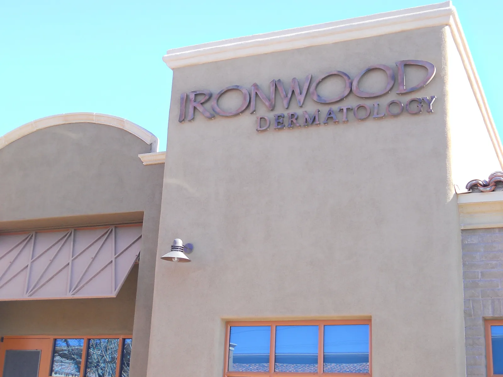 Exterior view of Ironwood Dermatology building with clear blue sky and visible windows and signage.