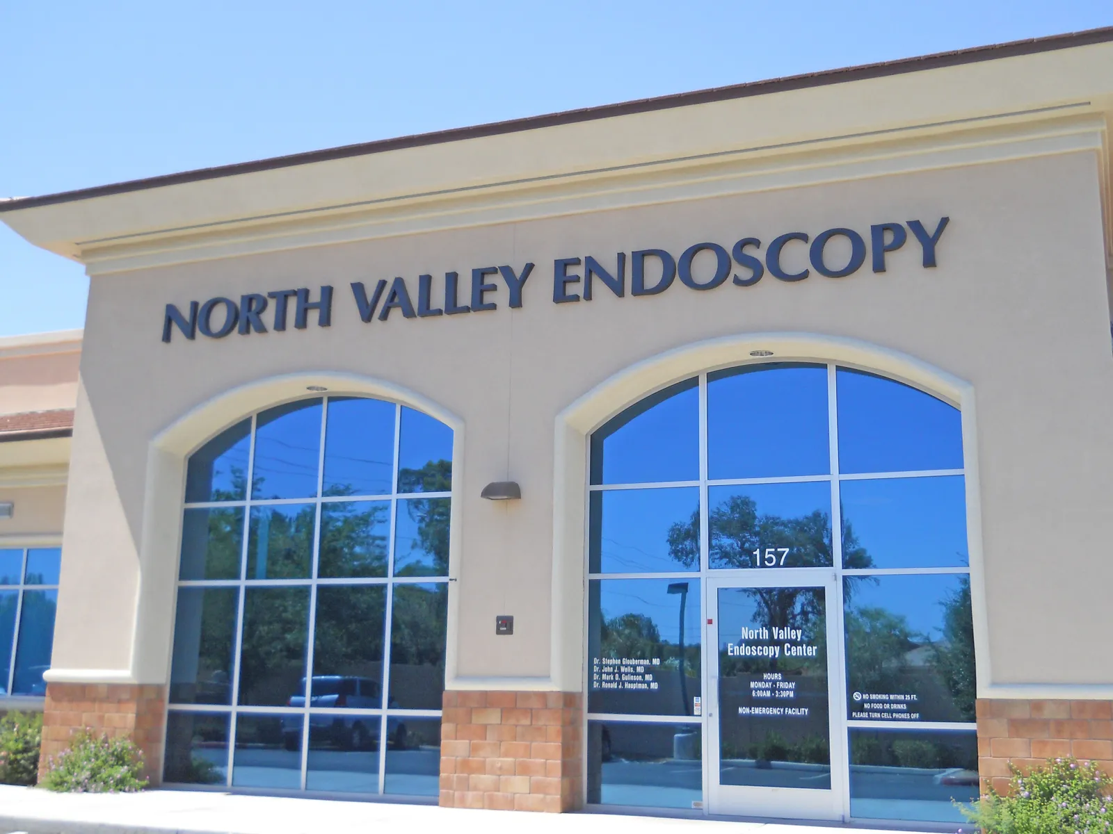Front exterior of North Valley Endoscopy Center with large windows and entrance door under clear blue sky.