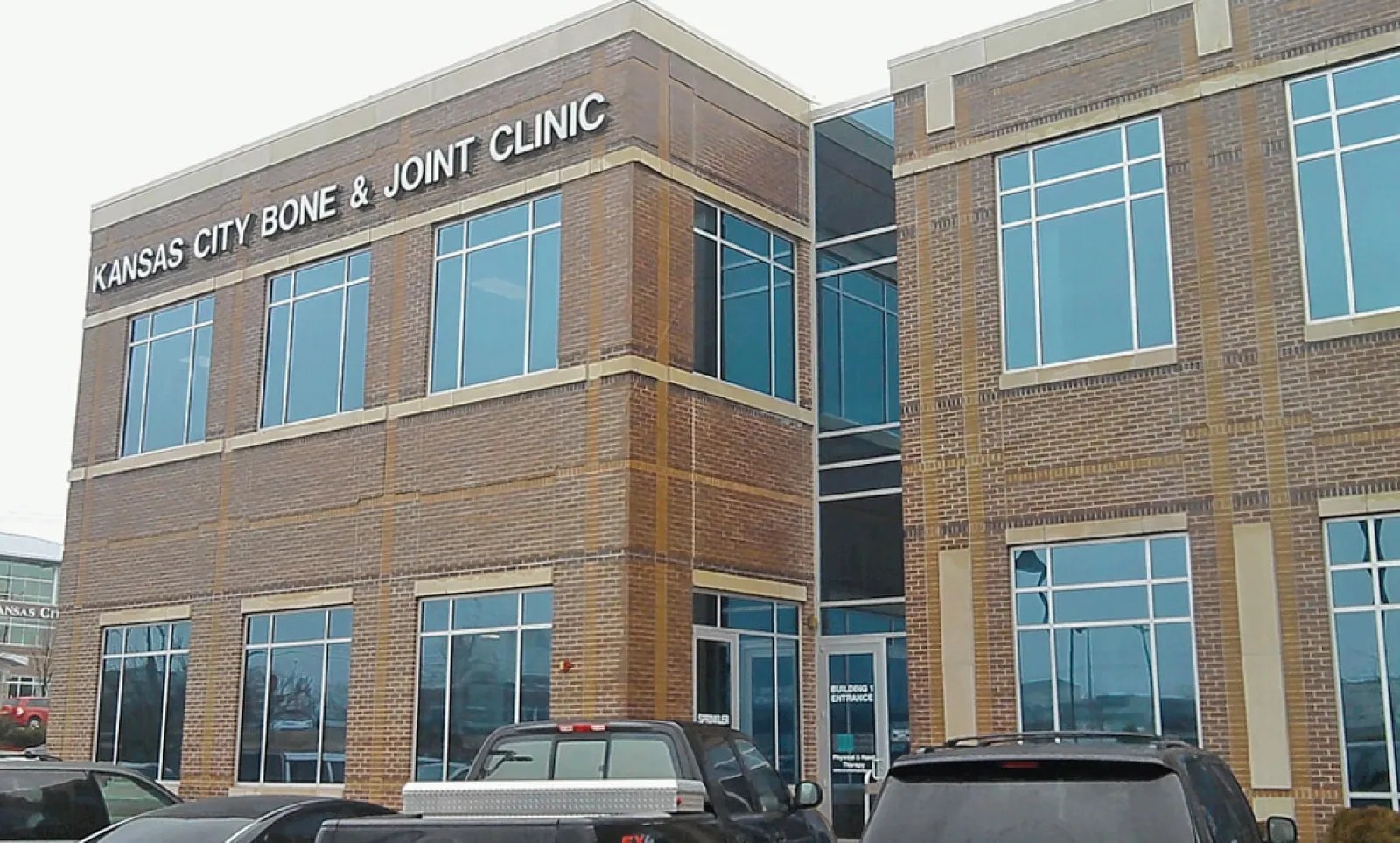 Exterior view of Kansas City Bone & Joint Clinic building with parked cars in front on a cloudy day