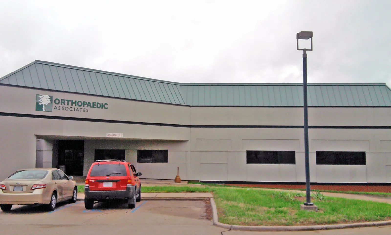 Orthopaedic Associates medical office building with parked cars and green roof under cloudy sky