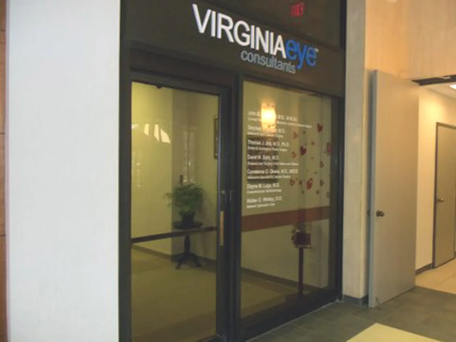 Glass entrance doors of Virginia Eye Consultants with visible office interior and potted plant inside.