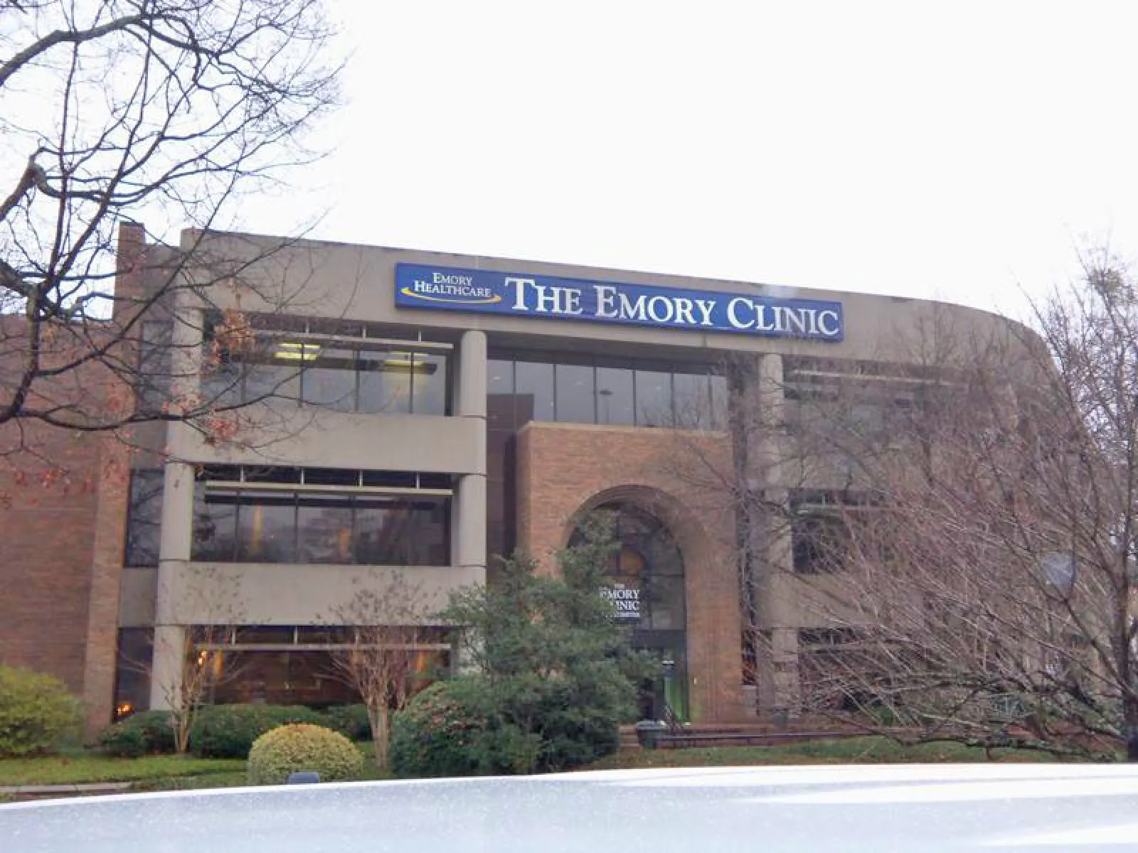 Exterior view of The Emory Clinic building with trees and bushes in front during winter.
