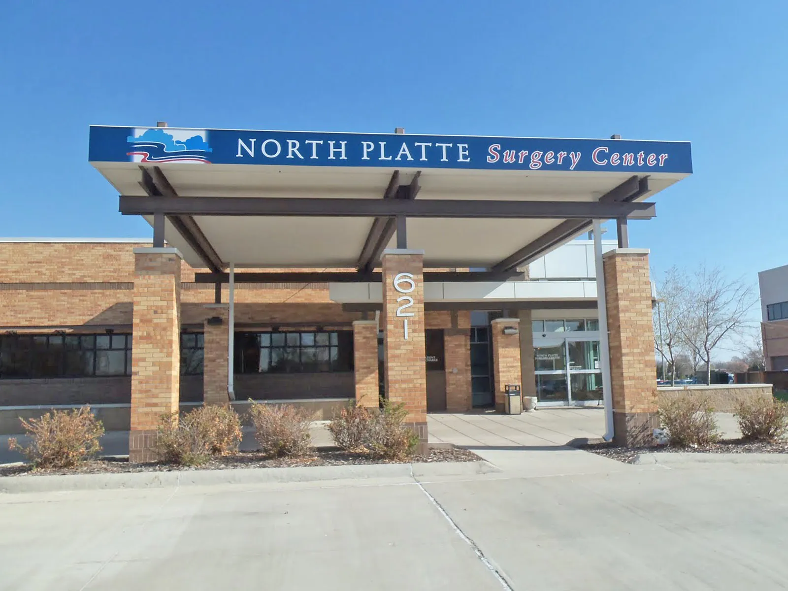 Entrance of North Platte Surgery Center with brick pillars and covered walkway under a clear blue sky