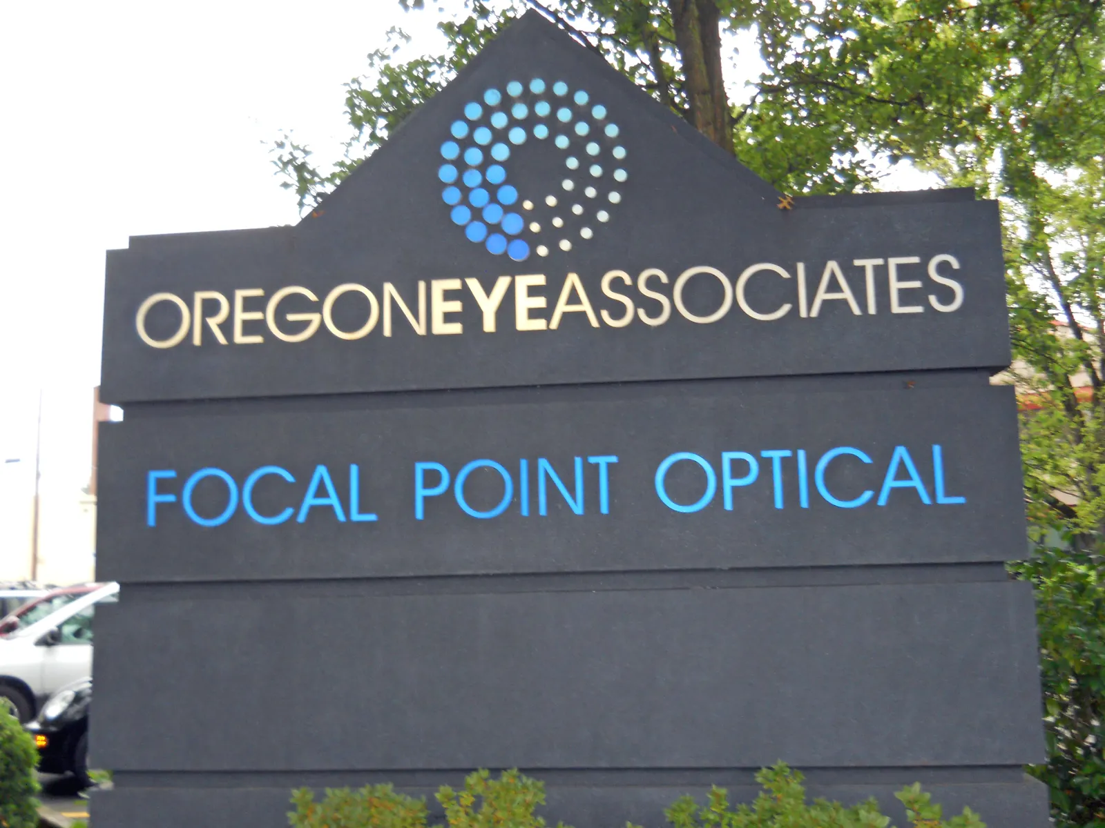 Oregon Eye Associates sign with blue circular logo and Focal Point Optical text on black background.