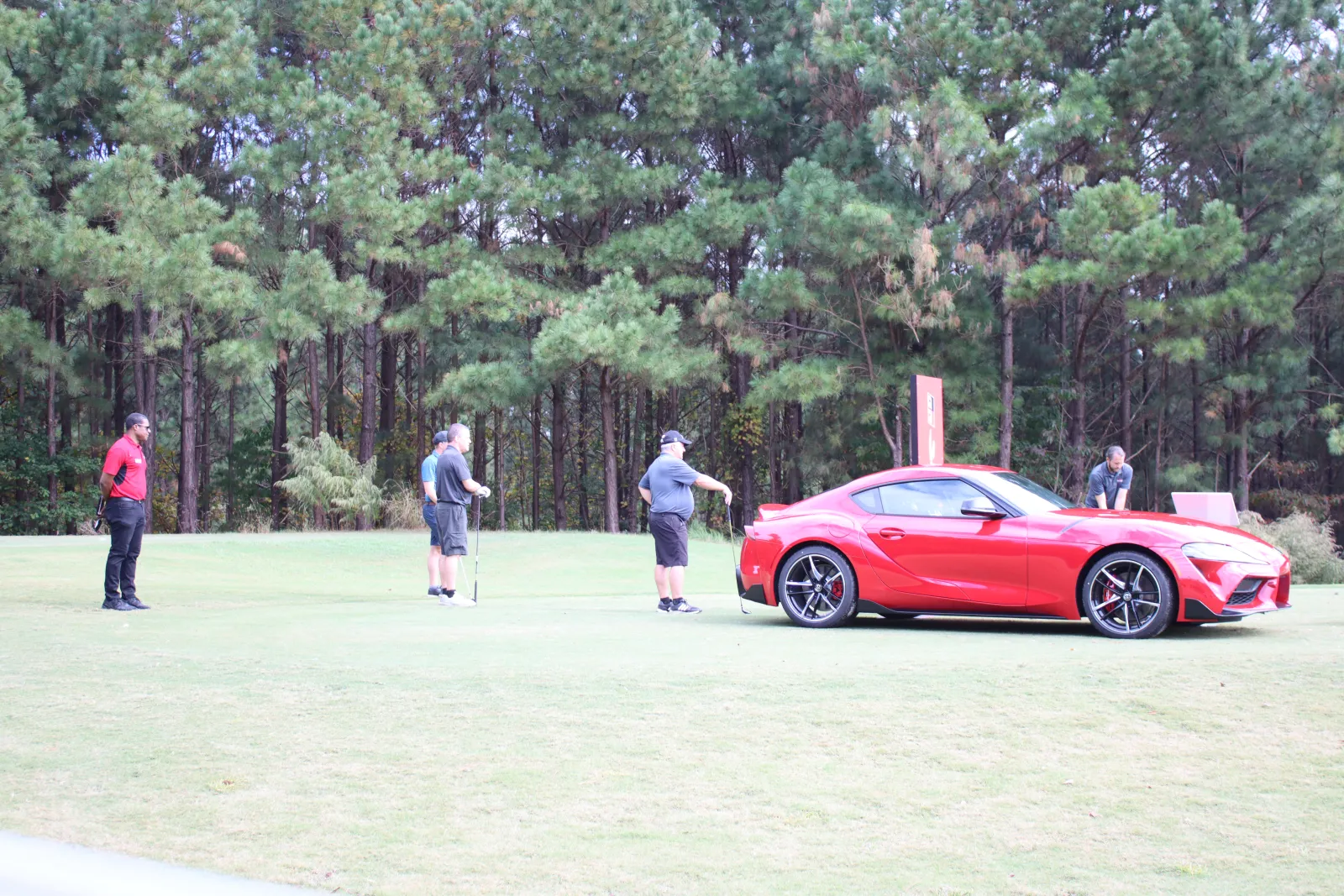 a group of people standing around a red sports car