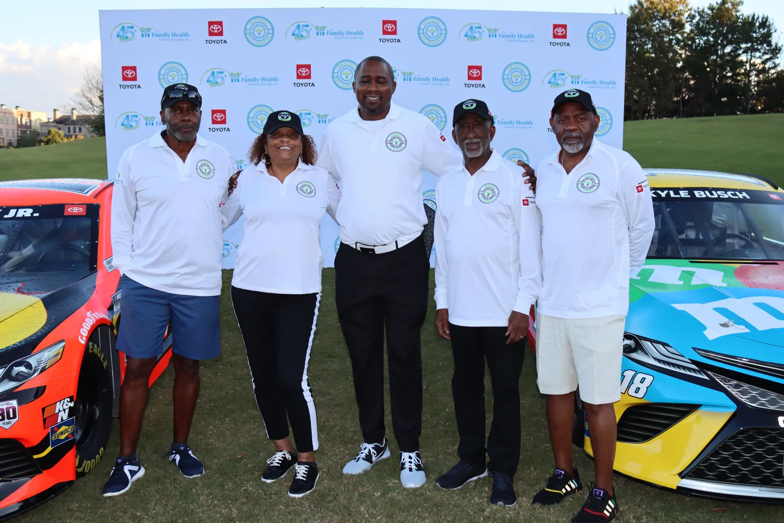 a group of people posing for a photo next to a race car