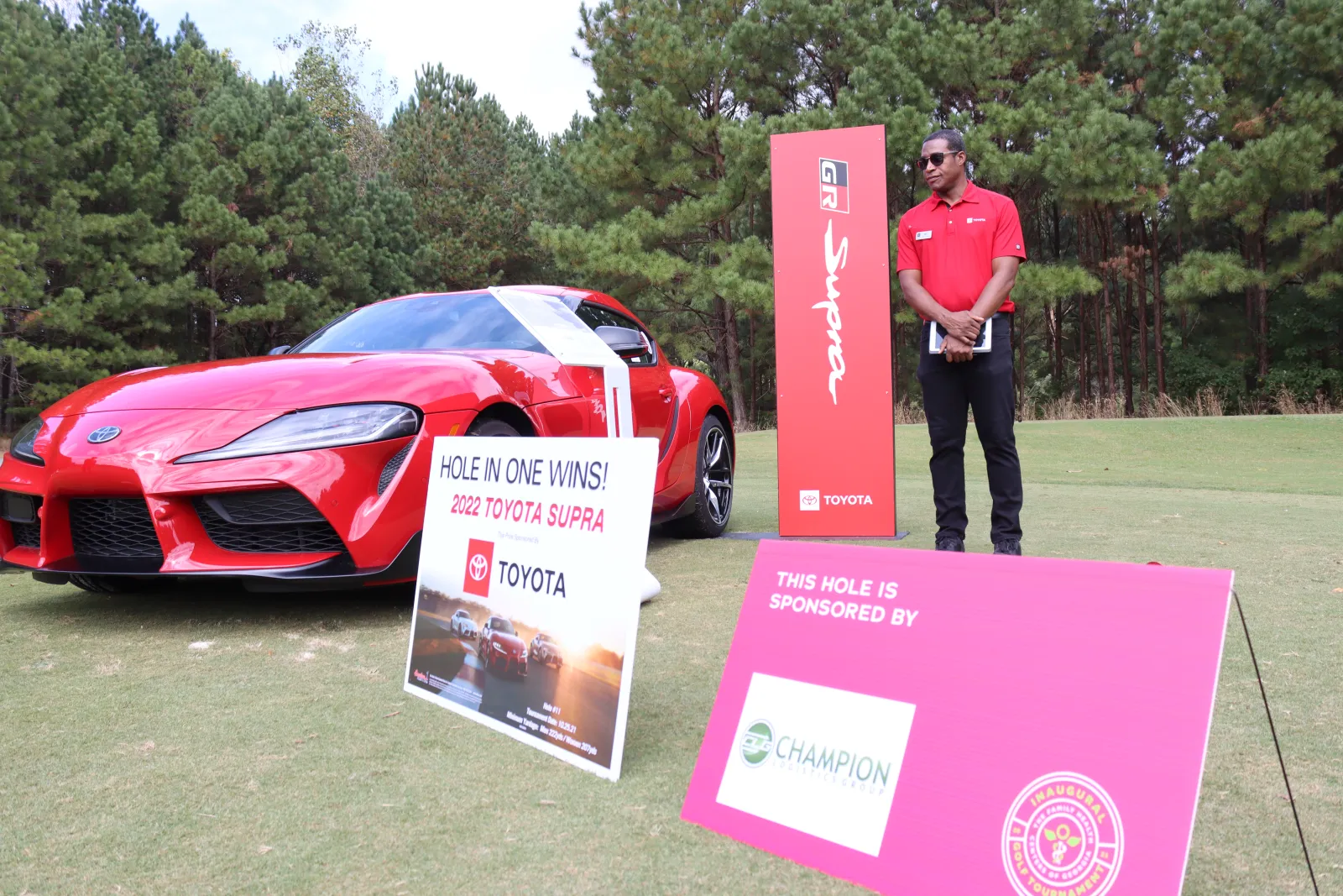 a person standing next to a red car and a sign