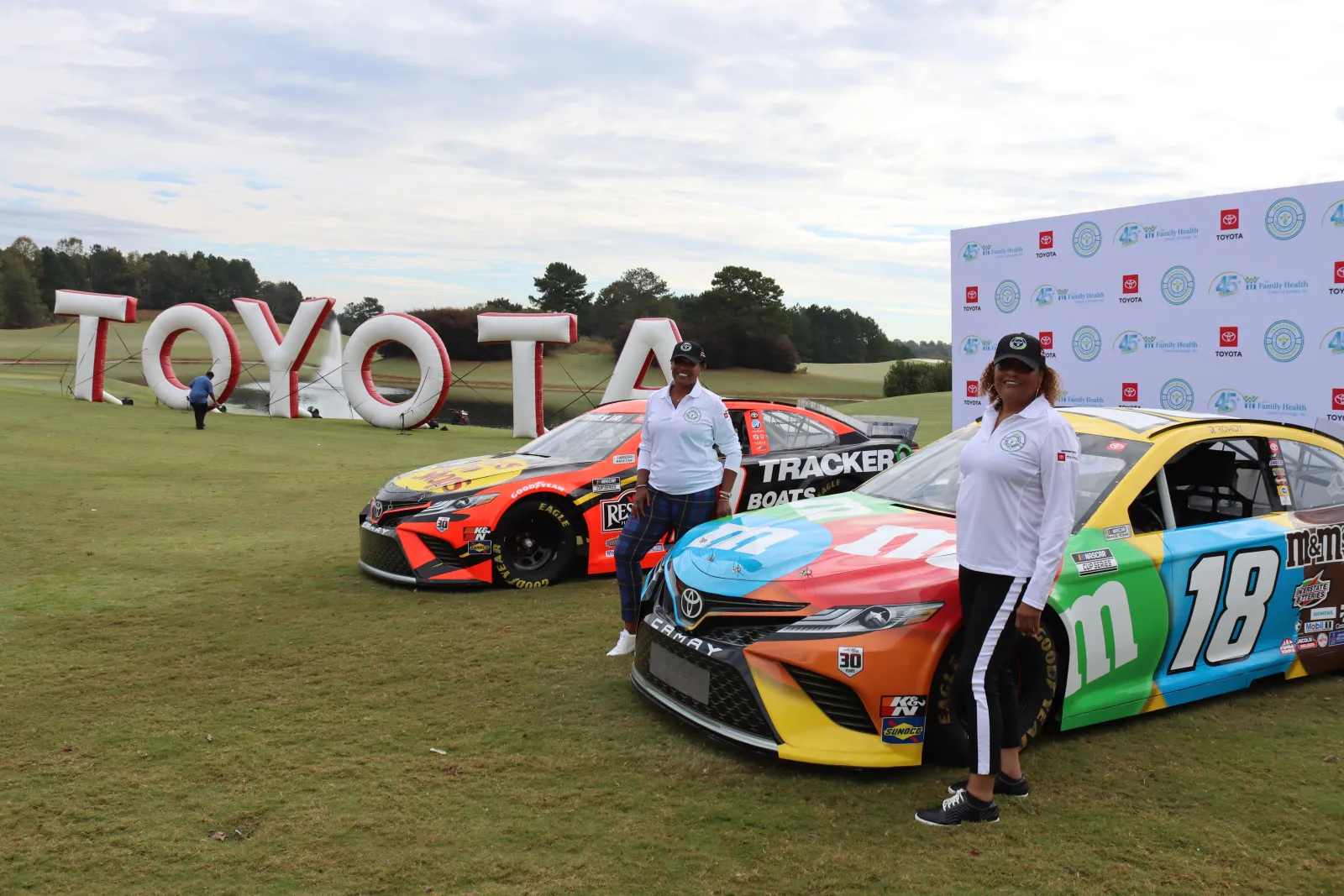 a couple of people standing next to a race car with a sign on it