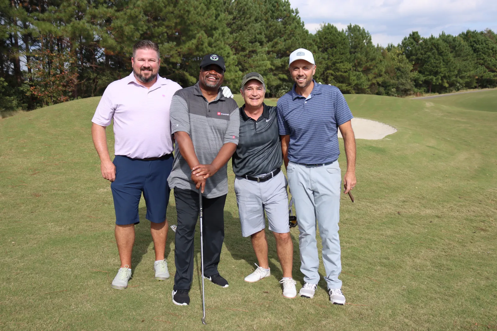 a group of men posing for a picture on a golf course