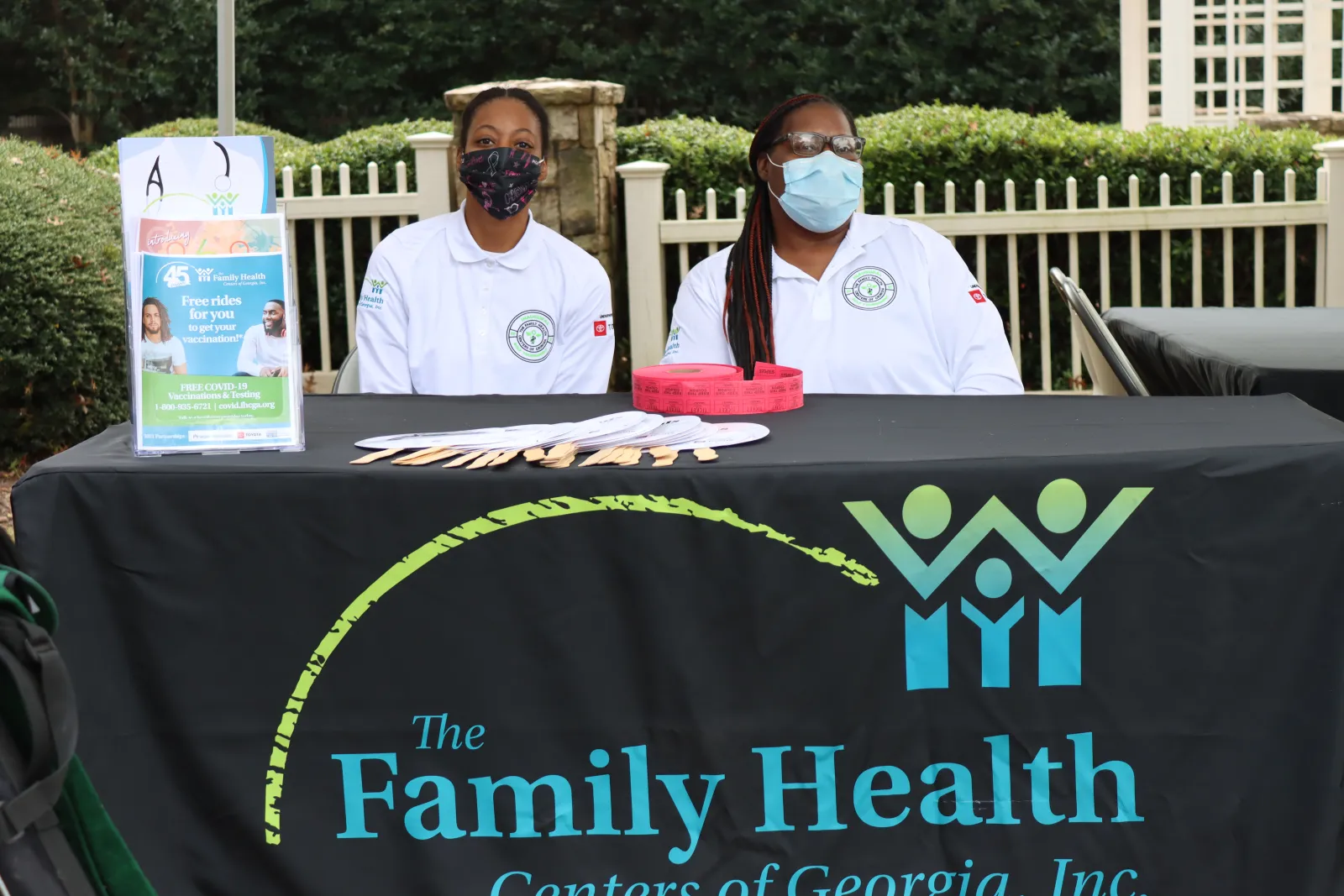 a couple of people wearing masks and sitting at a table with a sign