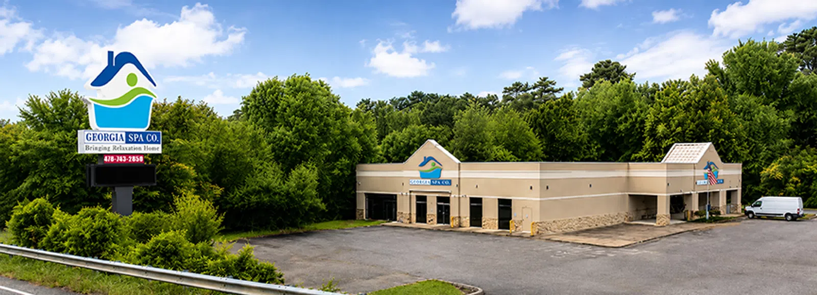 Exterior view of Georgia Spa Co building surrounded by trees under a blue sky with a large company sign nearby