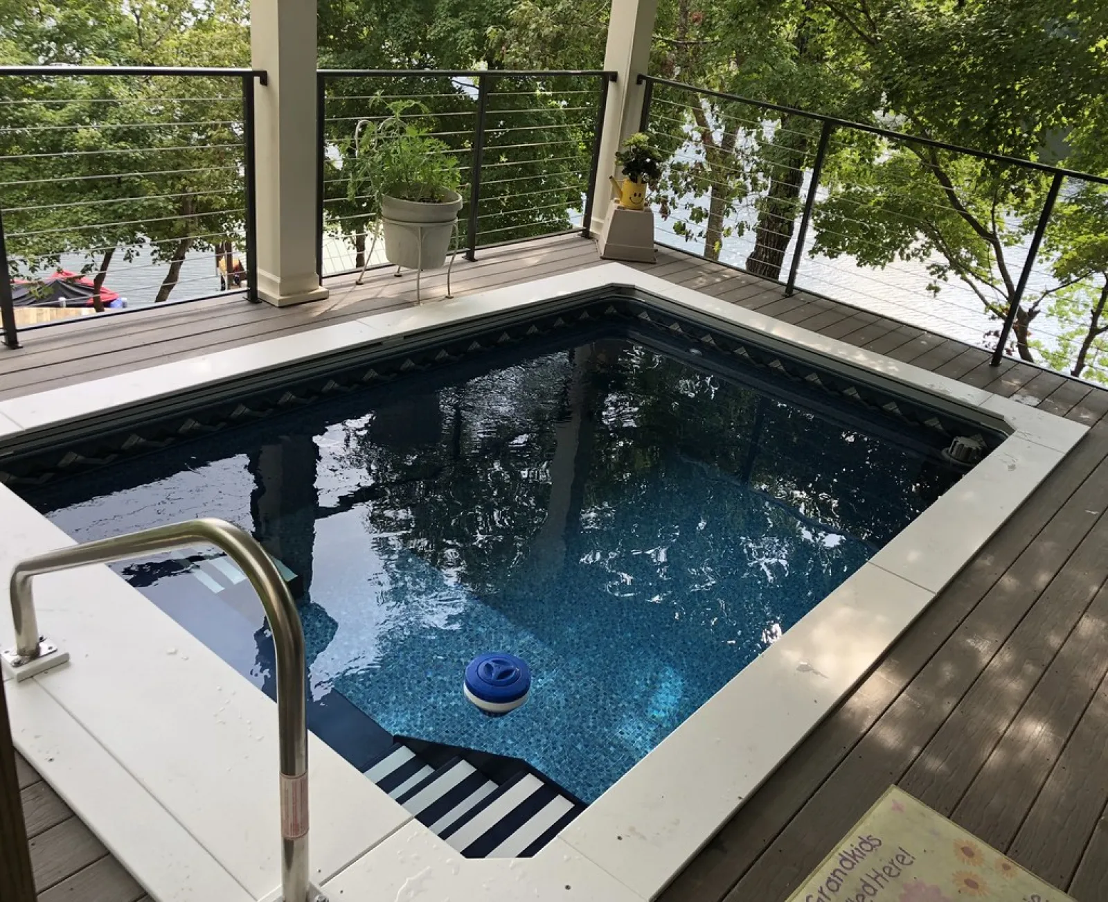 a pool with a deck and a deck with a railing and trees