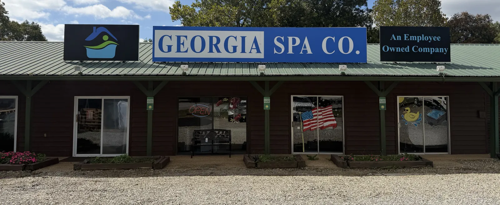 Exterior of Georgia Spa Co. building with signage, American flag, and a duck logo under a cloudy sky.