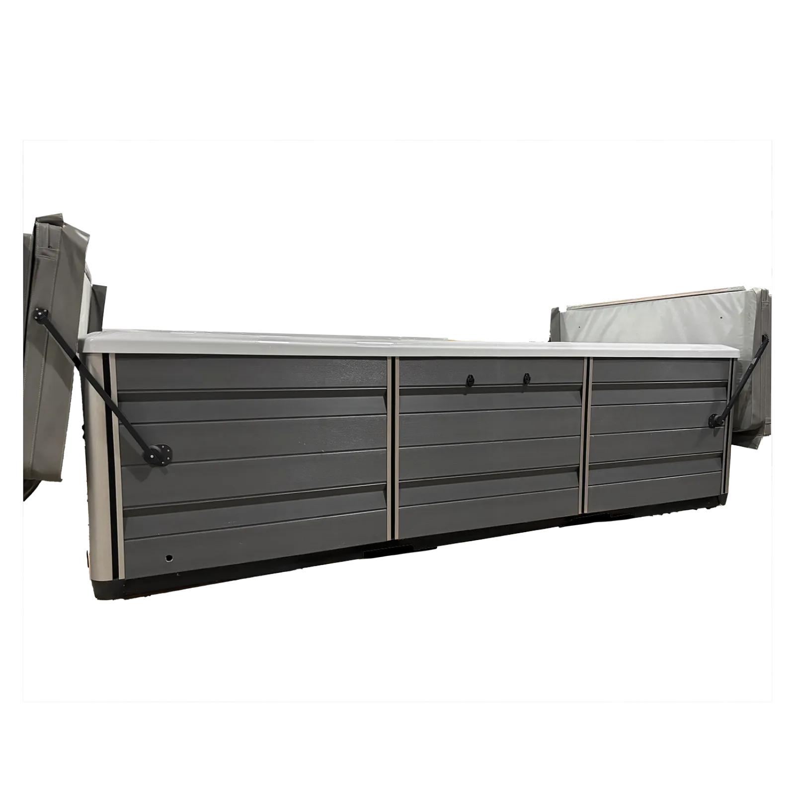 Long gray hot tub with white top and folded gray cushions on both ends isolated on black background
