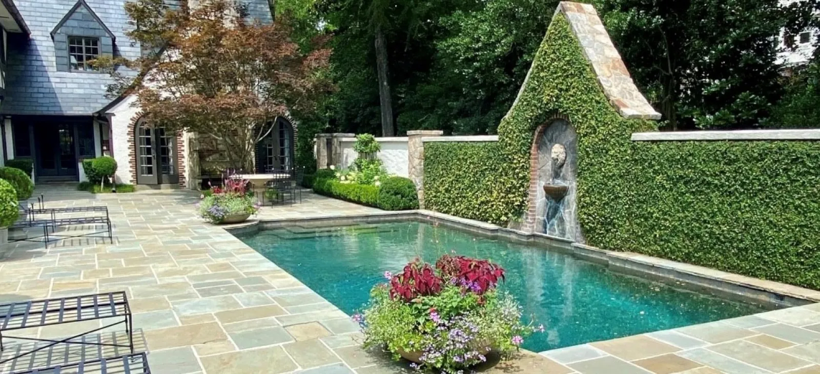 a pool with a statue in the middle of a yard with a house