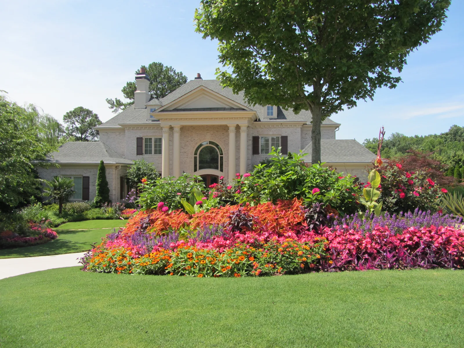 a large house with a large front yard and a large flower bed