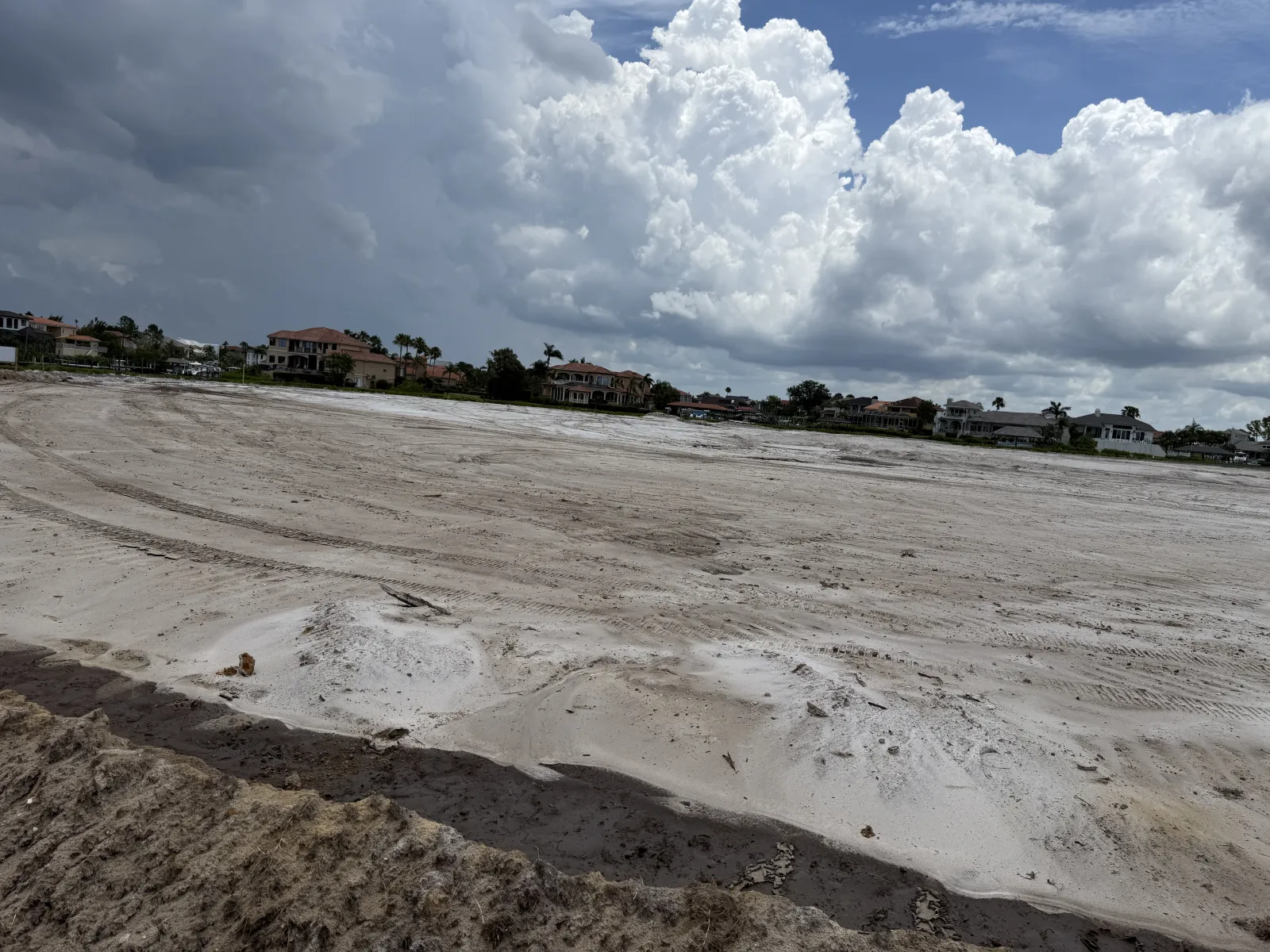 Cleared sandy construction site in a residential neighborhood under cloudy skies