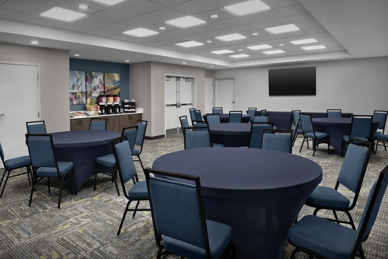 Modern conference room with round tables covered in dark cloths and blue chairs under bright ceiling lights