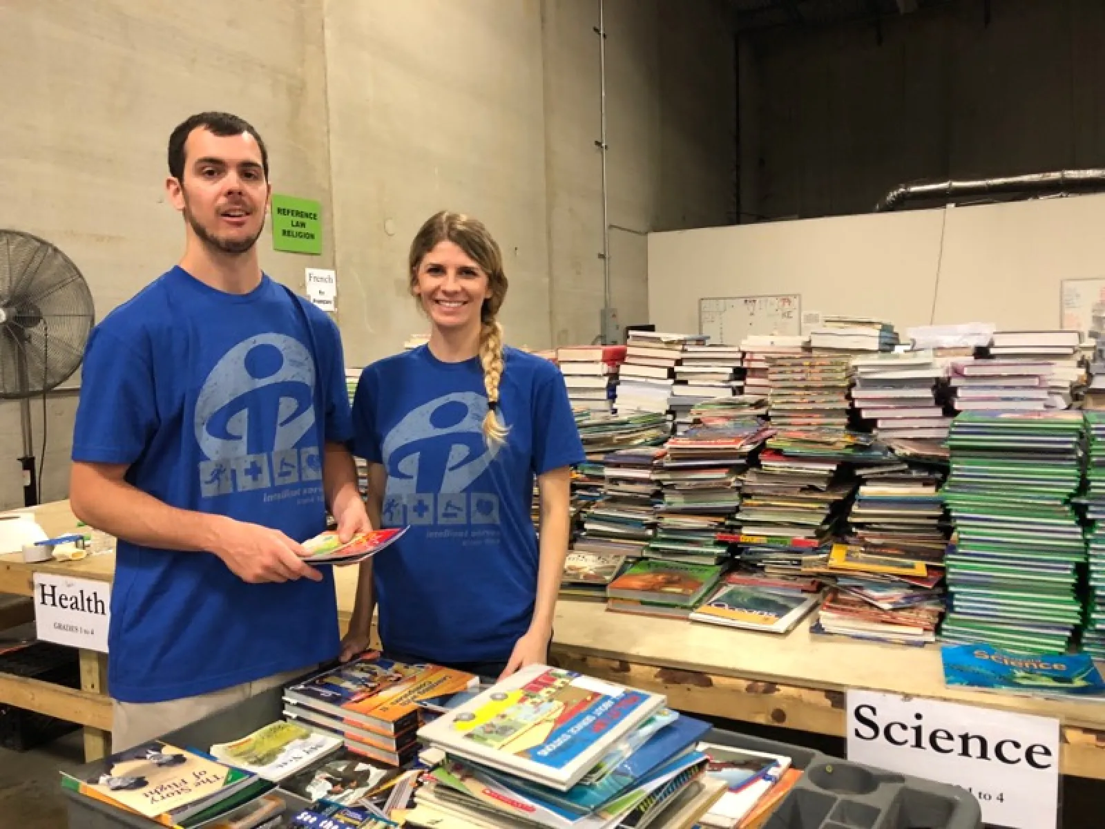 a man and a woman standing next to a table full of books