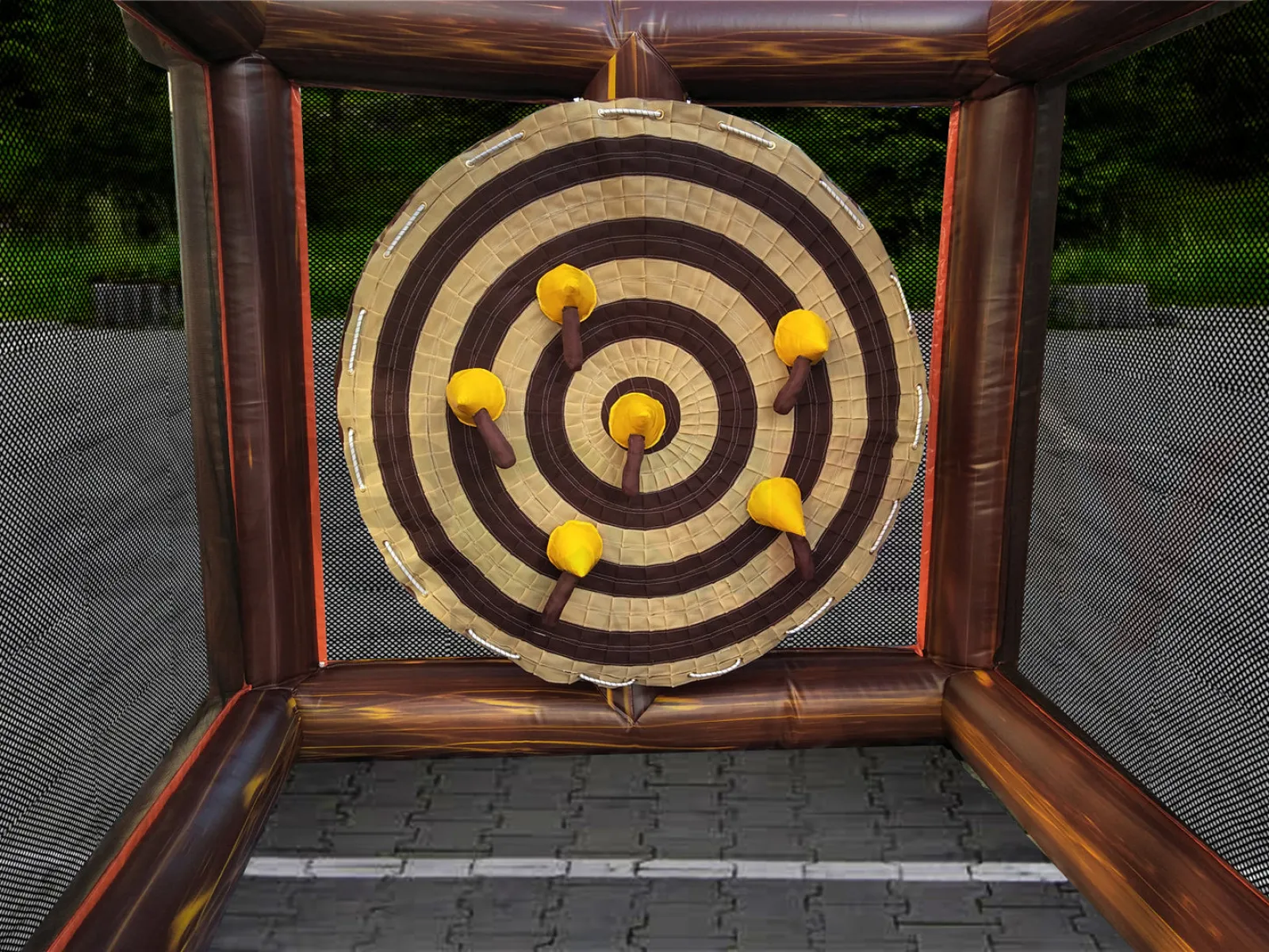 Inflatable axe throwing target with five axes stuck on different rings inside a netted enclosure outdoors.