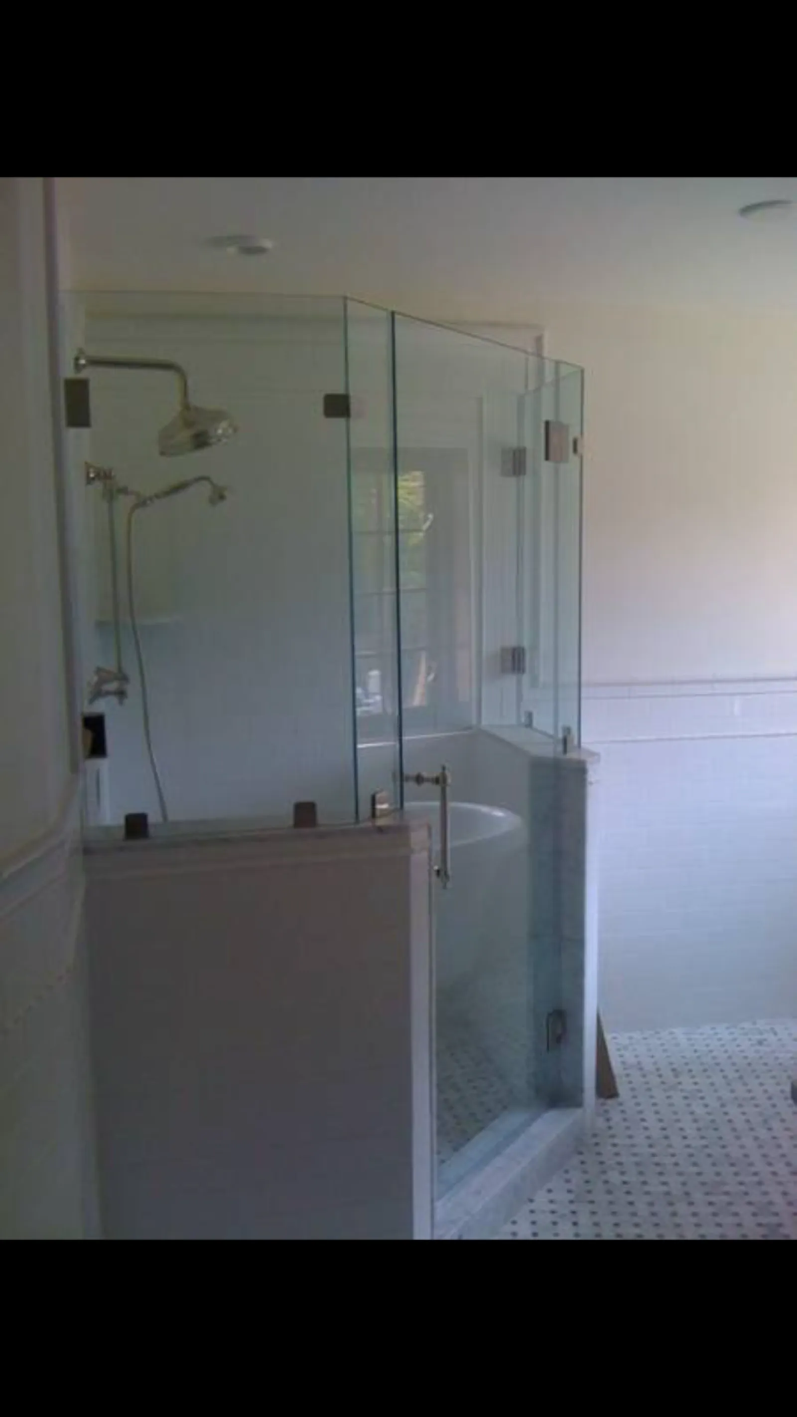 Modern bathroom with glass-enclosed shower and white tiled floor and walls.