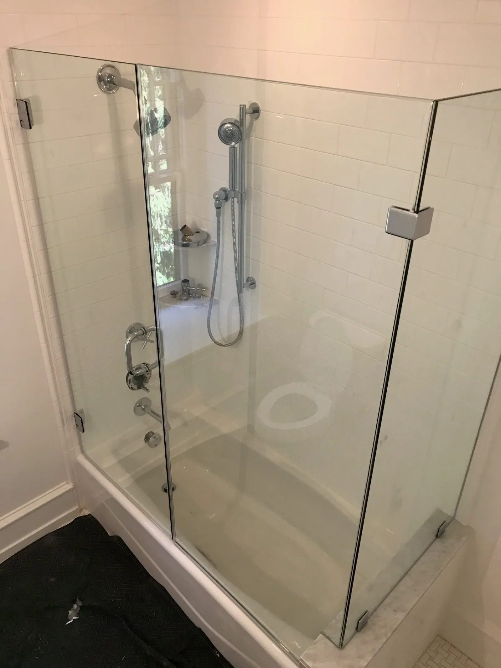 Modern bathroom featuring a glass shower enclosure with chrome fixtures and white tiled walls.