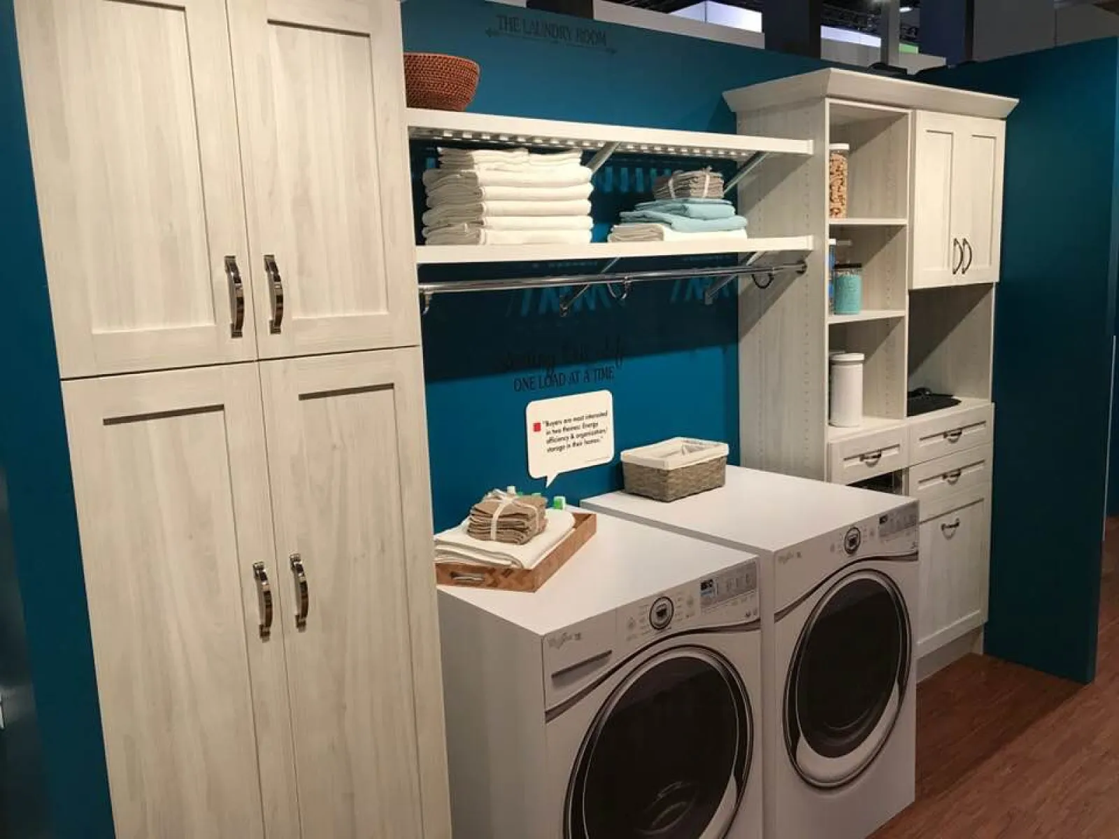 Modern laundry room with white cabinets, stacked towels, and front-loading washer and dryer units