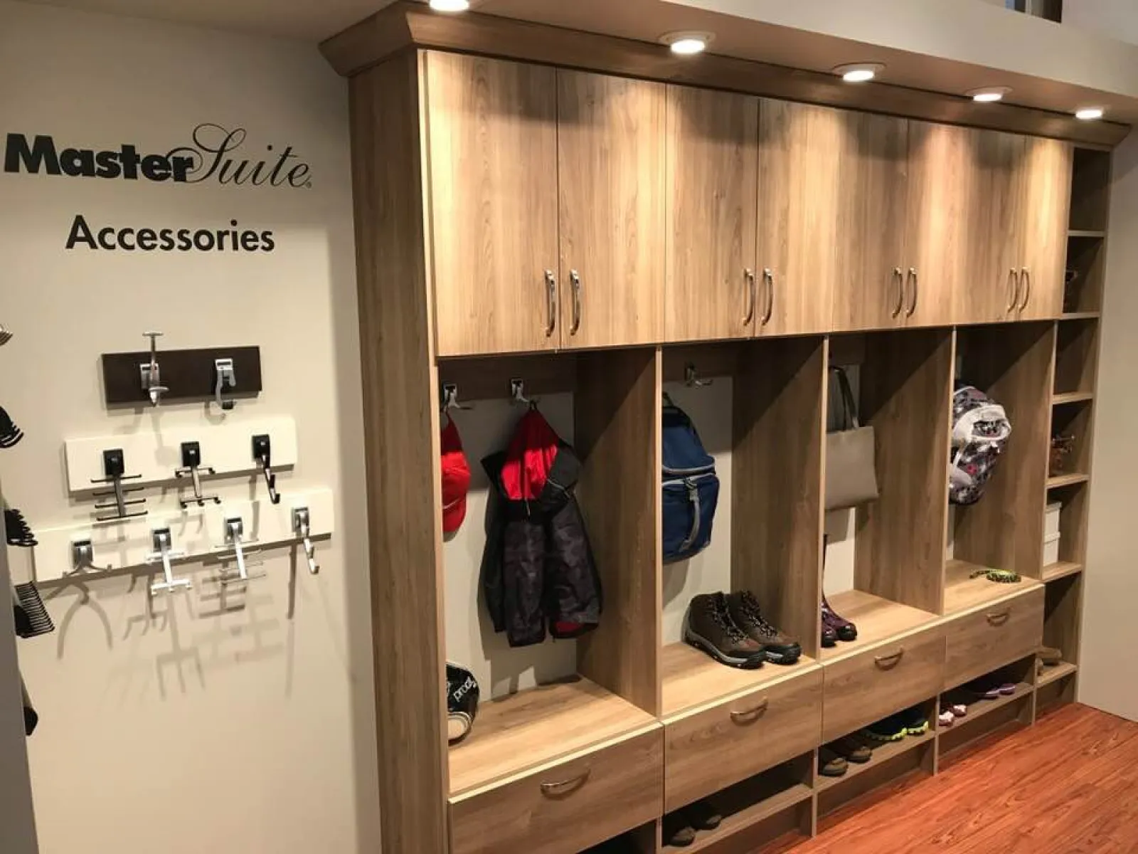 Wooden master suite storage with cabinets, hanging jackets, backpacks, shoes, and closet accessories on display.