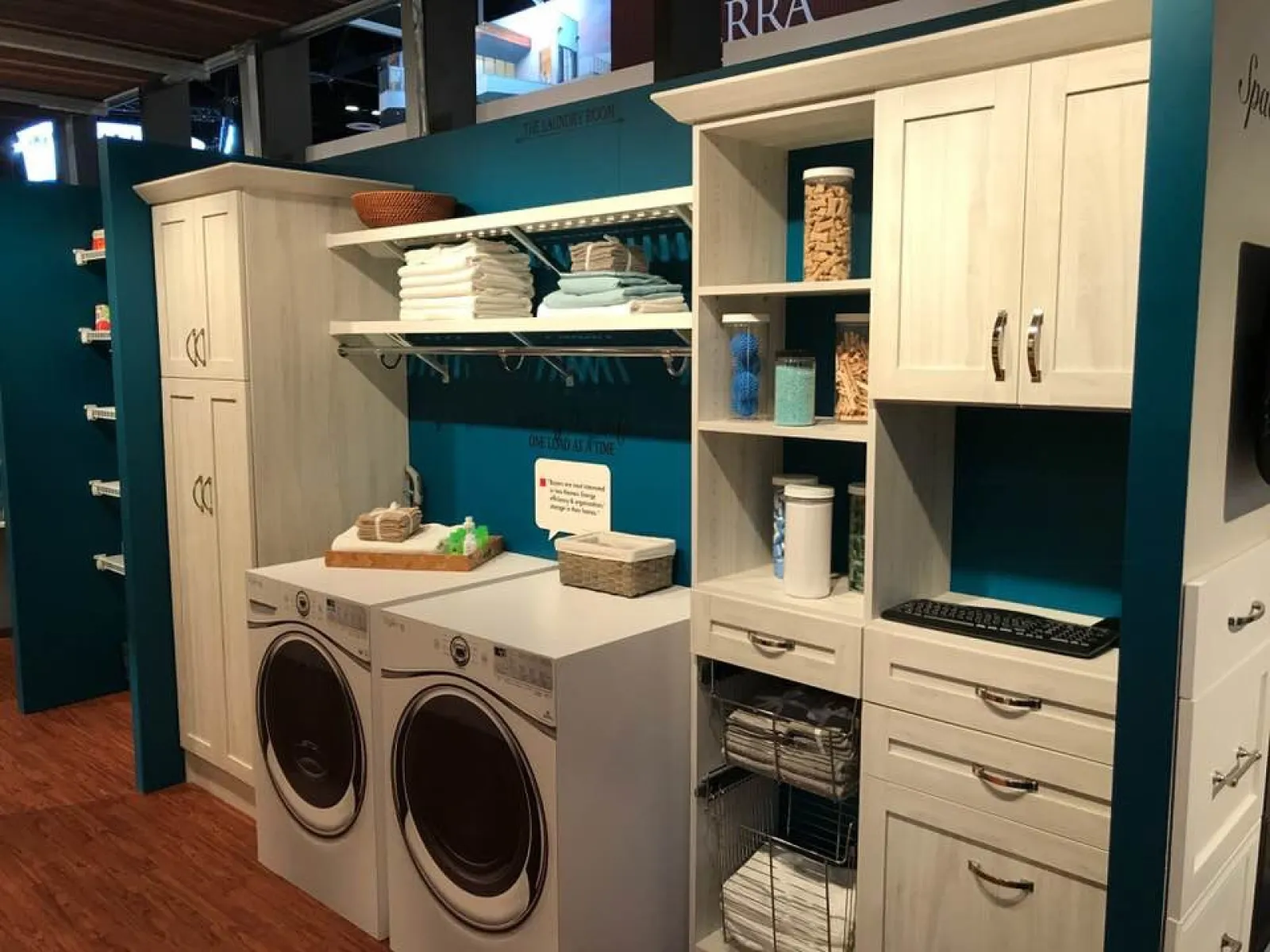 Modern laundry room with front-load washer and dryer, organized shelves, cabinets, and folded towels.