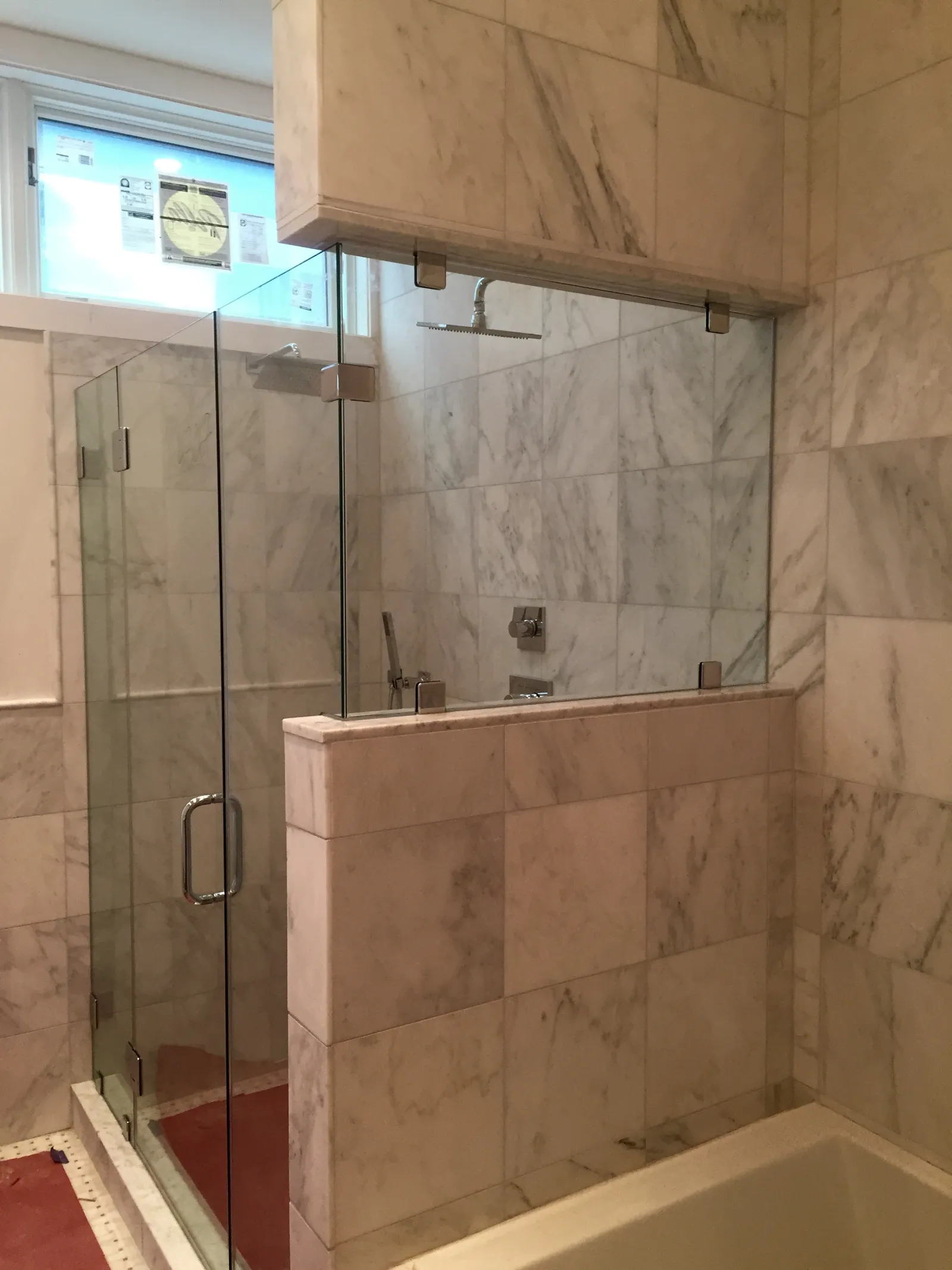 Modern bathroom with marble tile walls and glass shower enclosure featuring a rain showerhead.