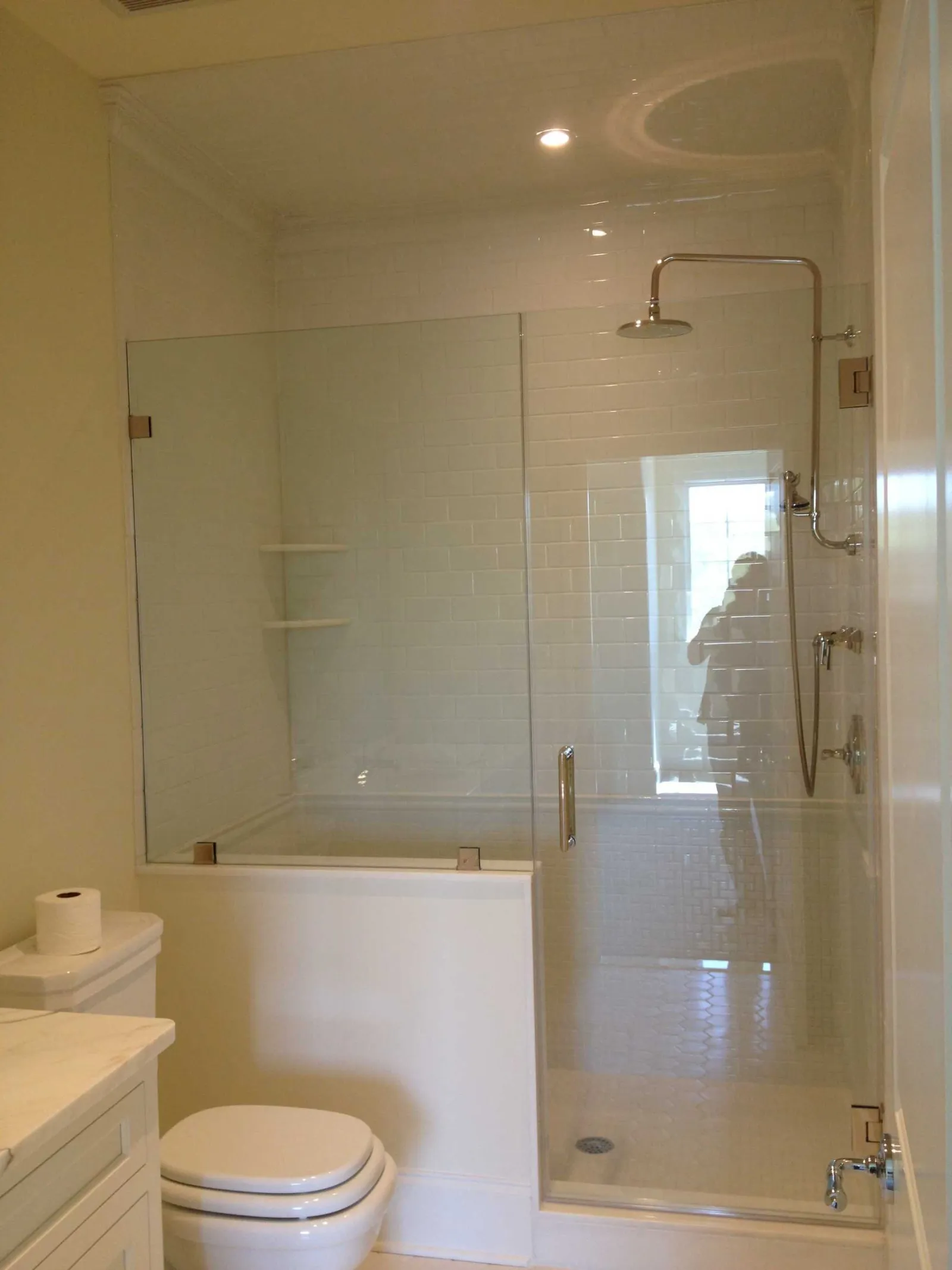 Modern bathroom with glass-enclosed shower, white subway tiles, toilet, and marble countertop vanity.