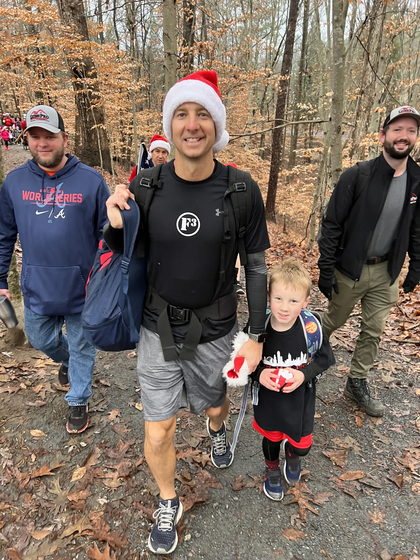 a group of people walking on a trail in the woods