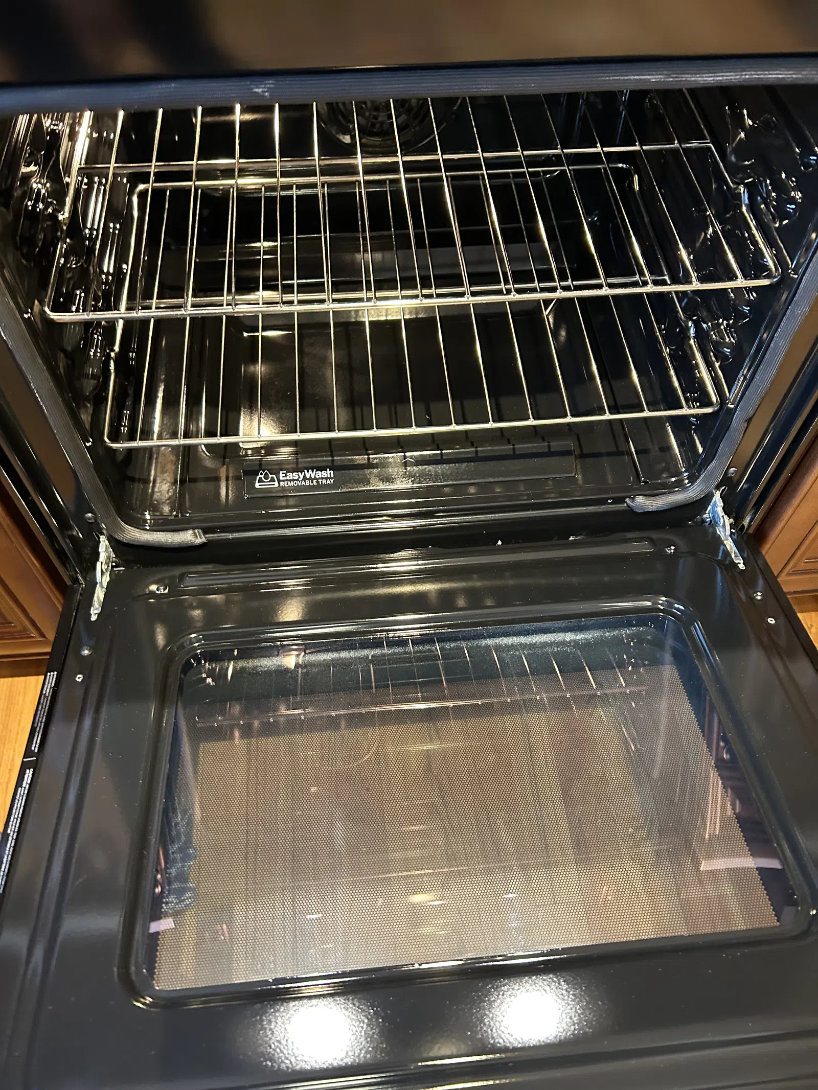 Open clean oven with two metal racks and Easy Wash removable tray inside a kitchen appliance.