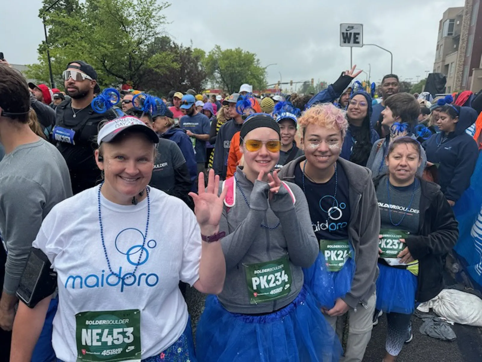 Group of diverse runners in race gear and blue tutus smiling and posing before the Bolder Boulder race.