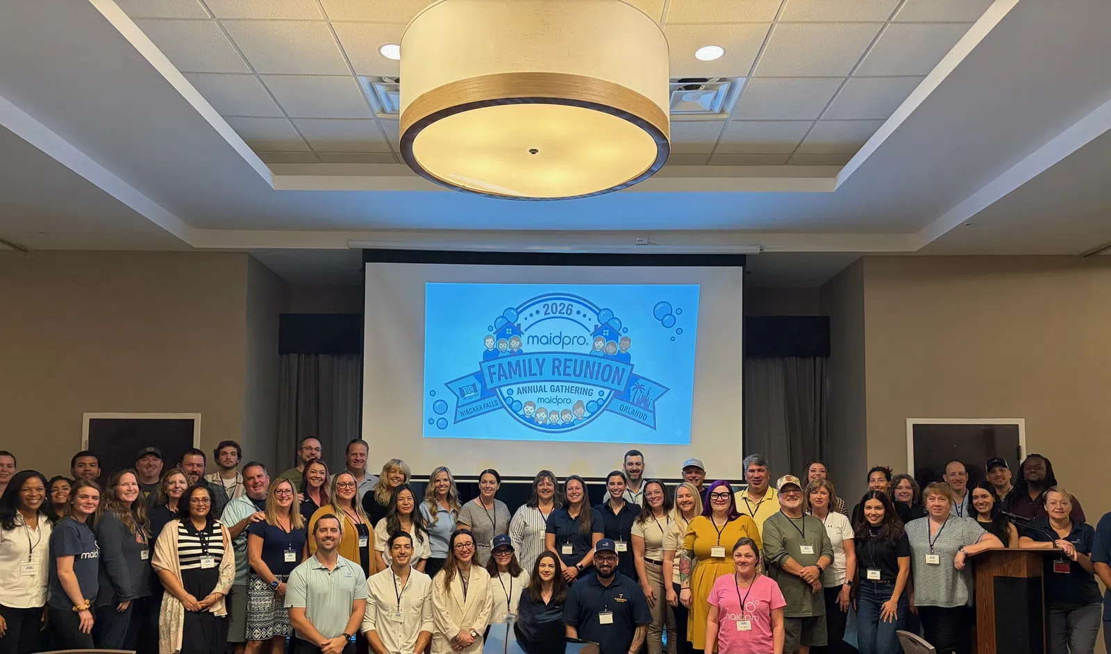 Large group photo at 2026 MaidPro family reunion annual gathering with overlaid event title on screen