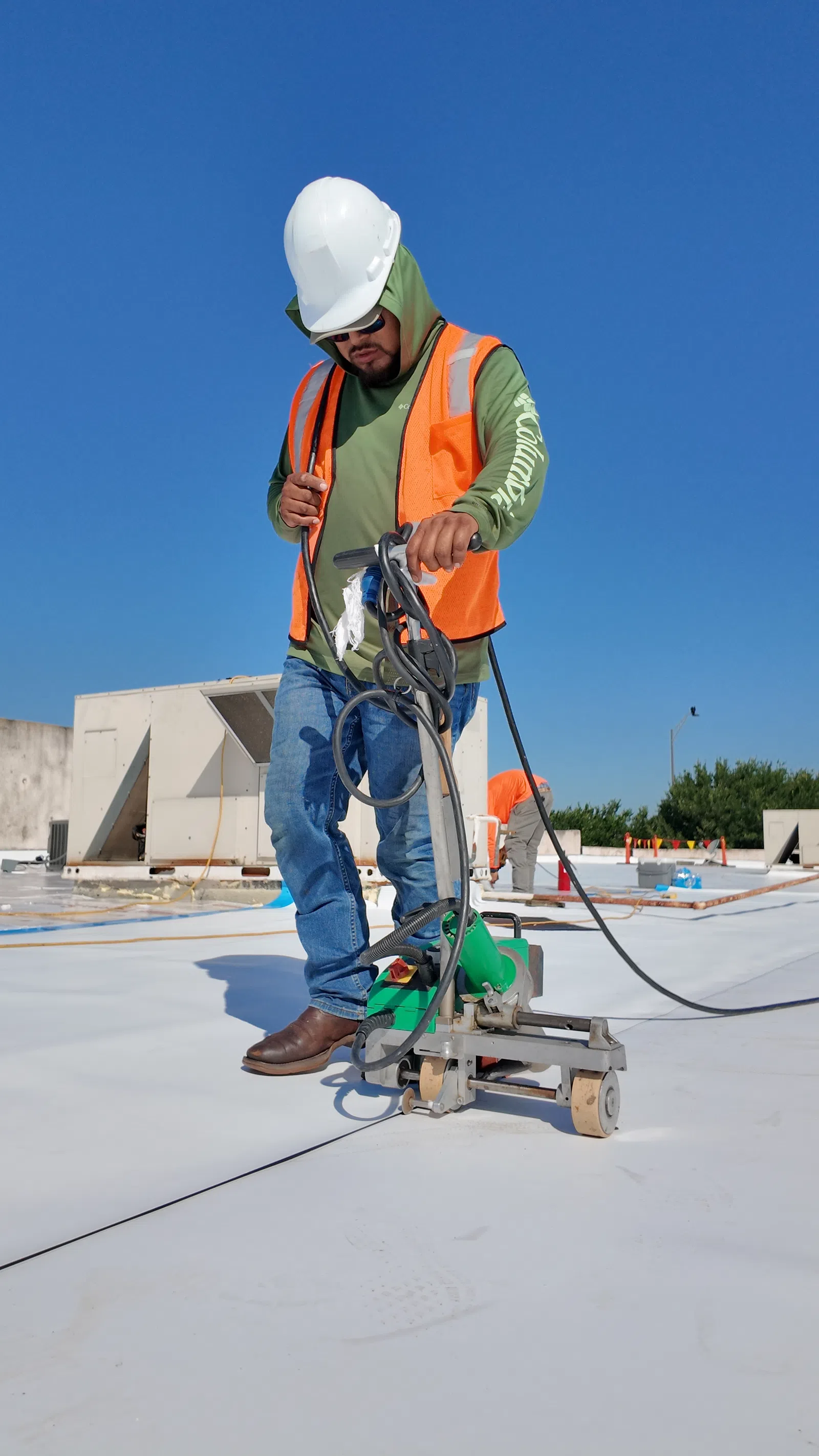 Close-up of a certified roofer using a heat welder to seal TPO roofing membrane seams