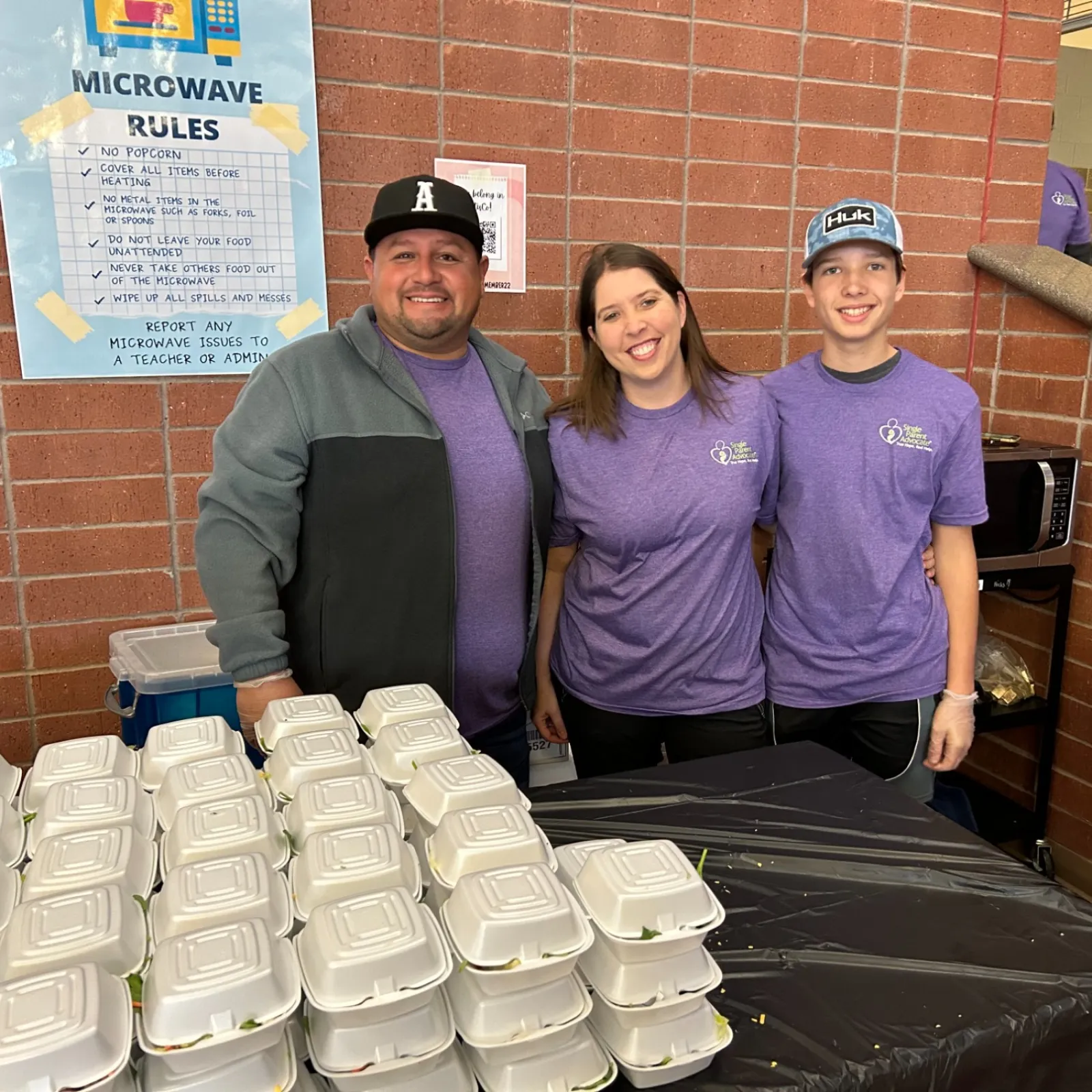 a group of people standing next to a table with white containers