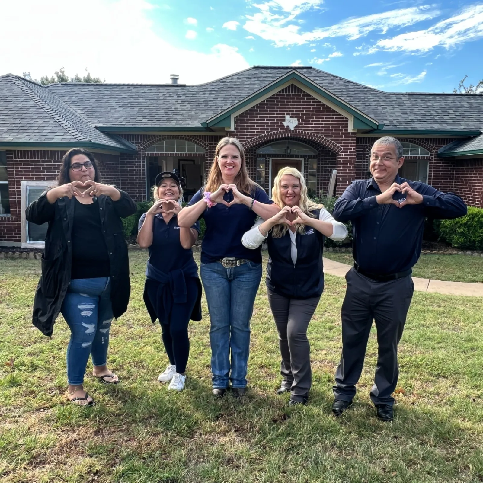 a group of people posing for a photo in front of a house