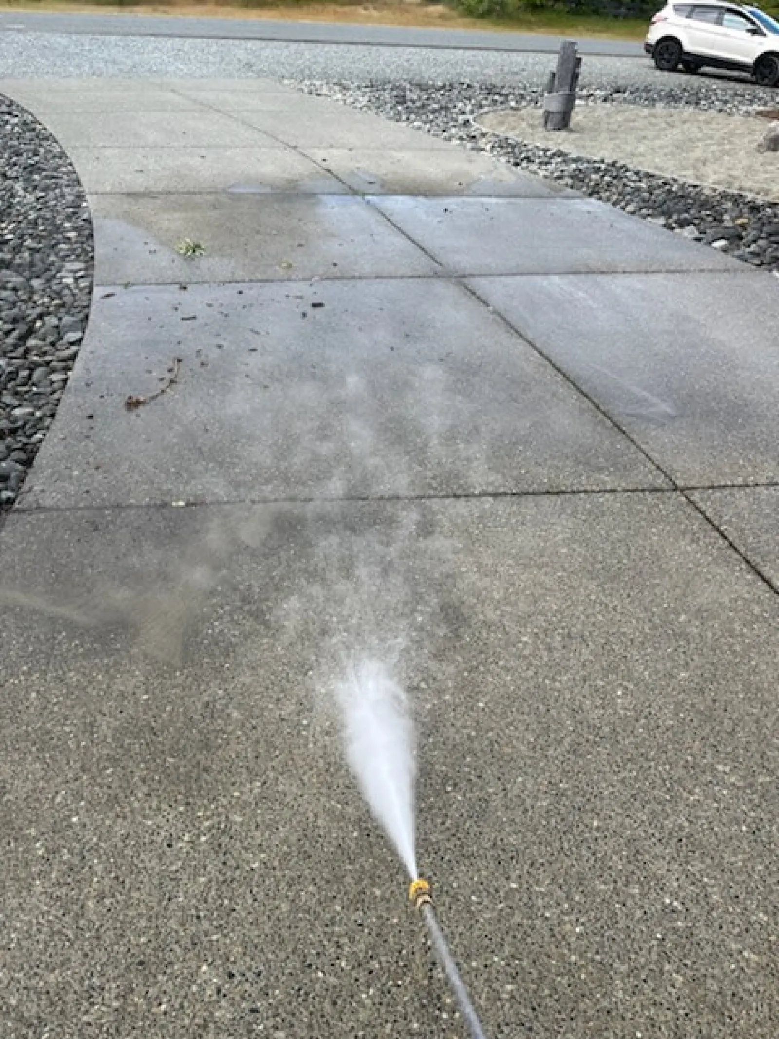 a white sprinkler spraying water on a sidewalk