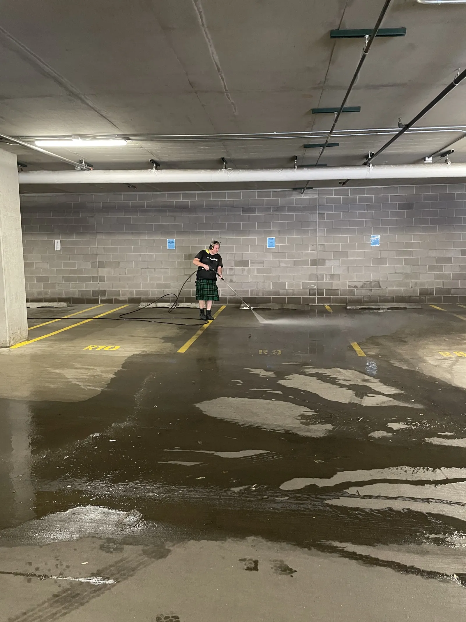 a man holding a broom in a parking garage