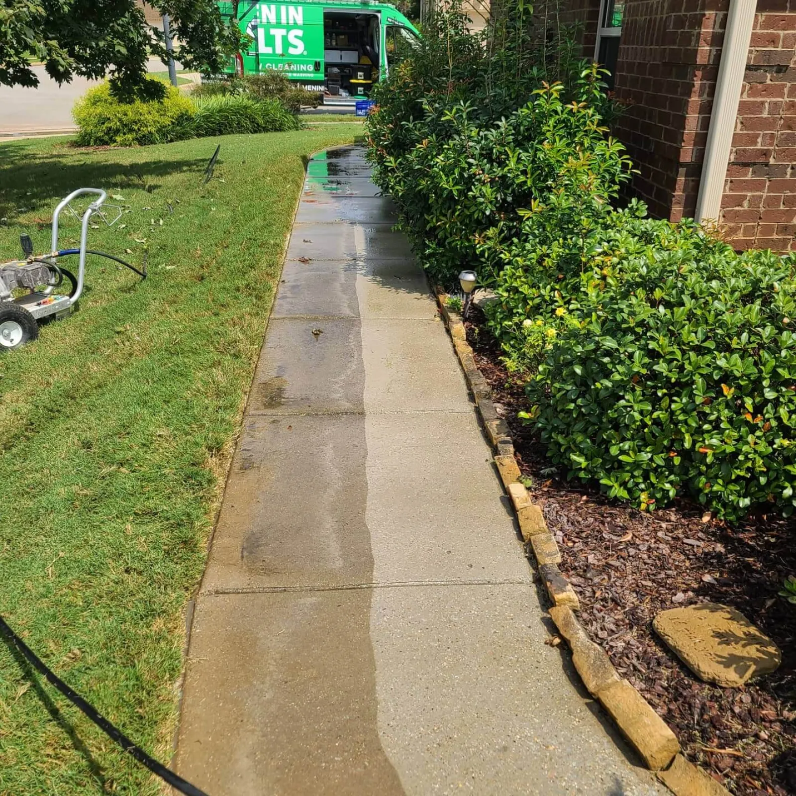 a sidewalk with bushes and a bus