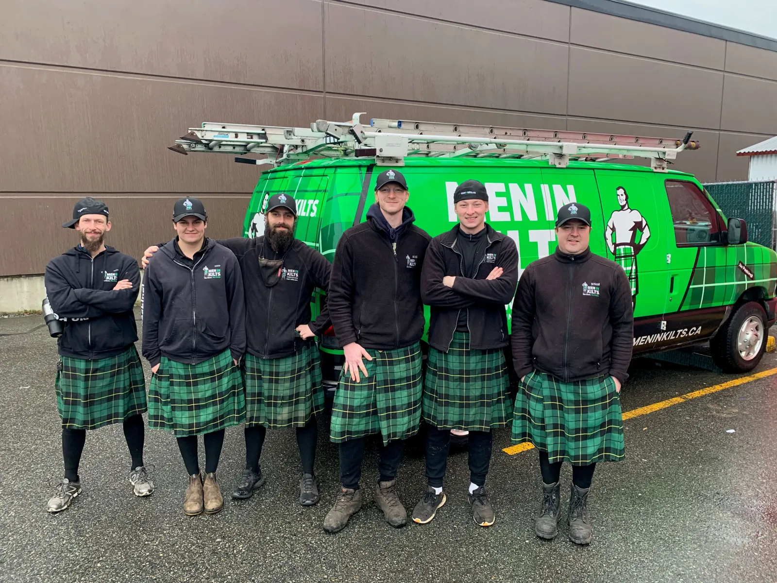 a group of men in kilts standing in front of a green truck