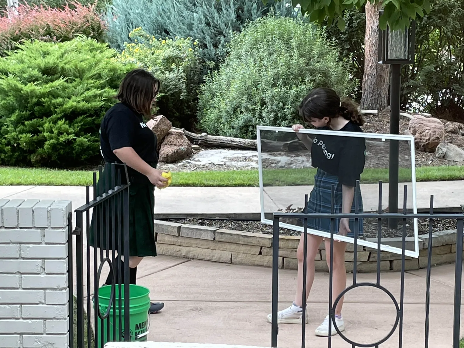 a couple of girls standing on a metal fence