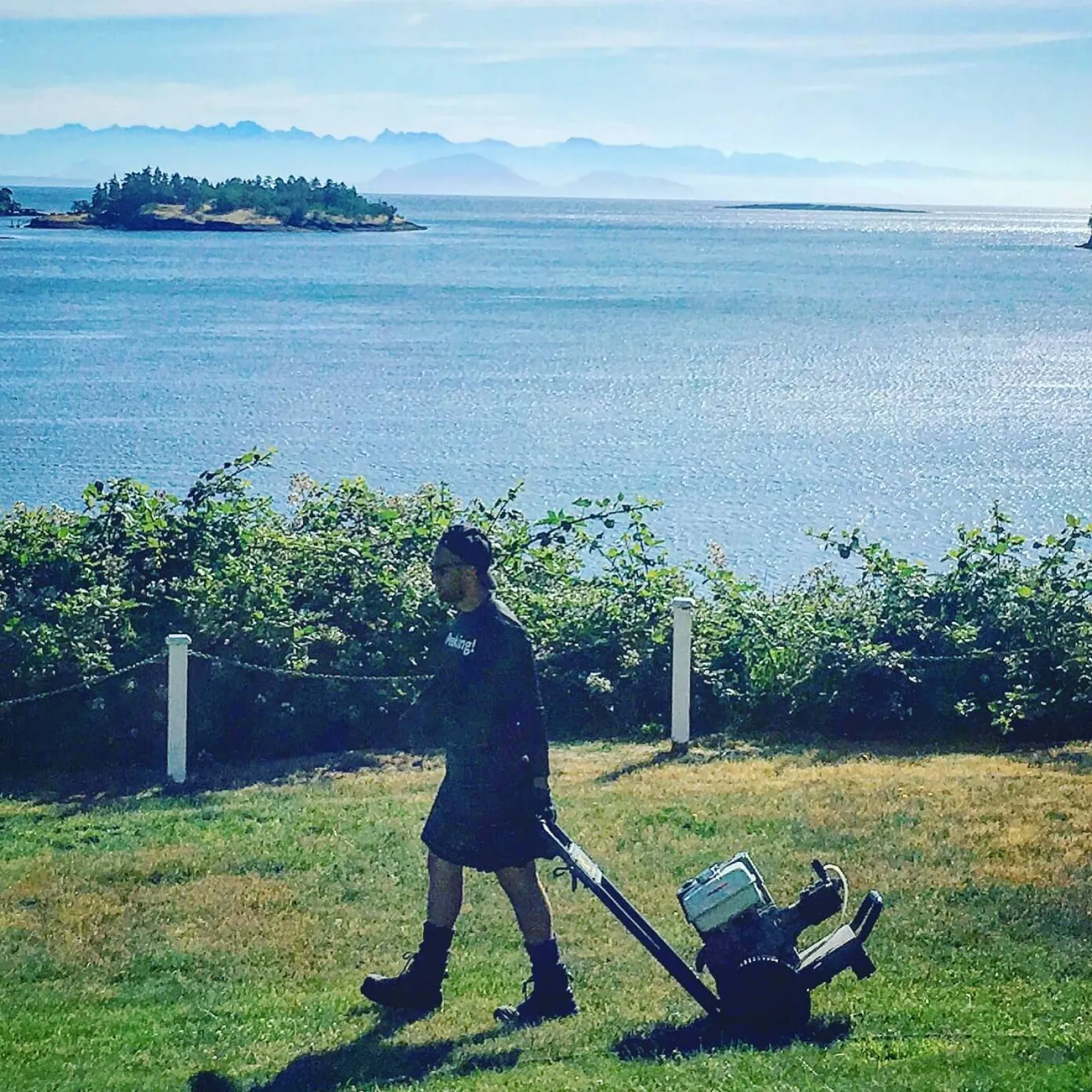 a person standing next to a bush with a body of water in the background