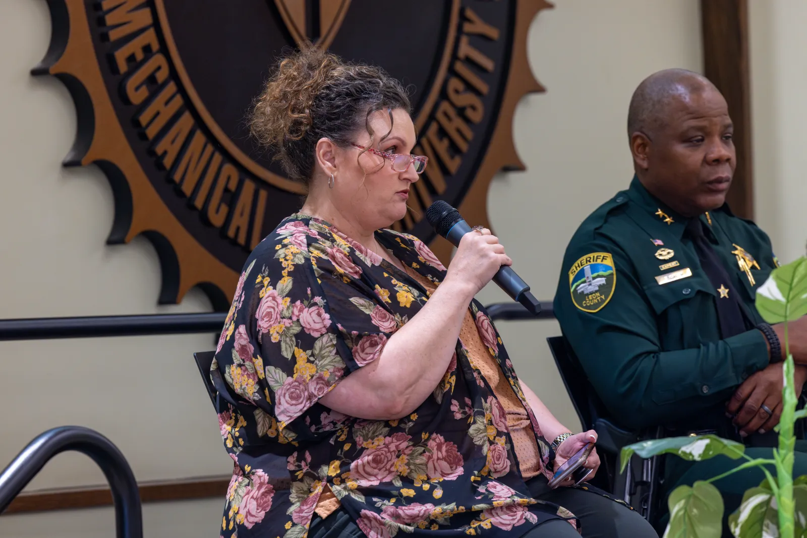 a person in a floral dress speaking into a microphone