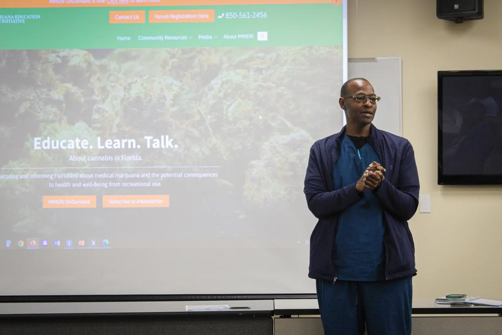 Man giving a presentation on educating about cannabis in Florida in front of a projection screen.